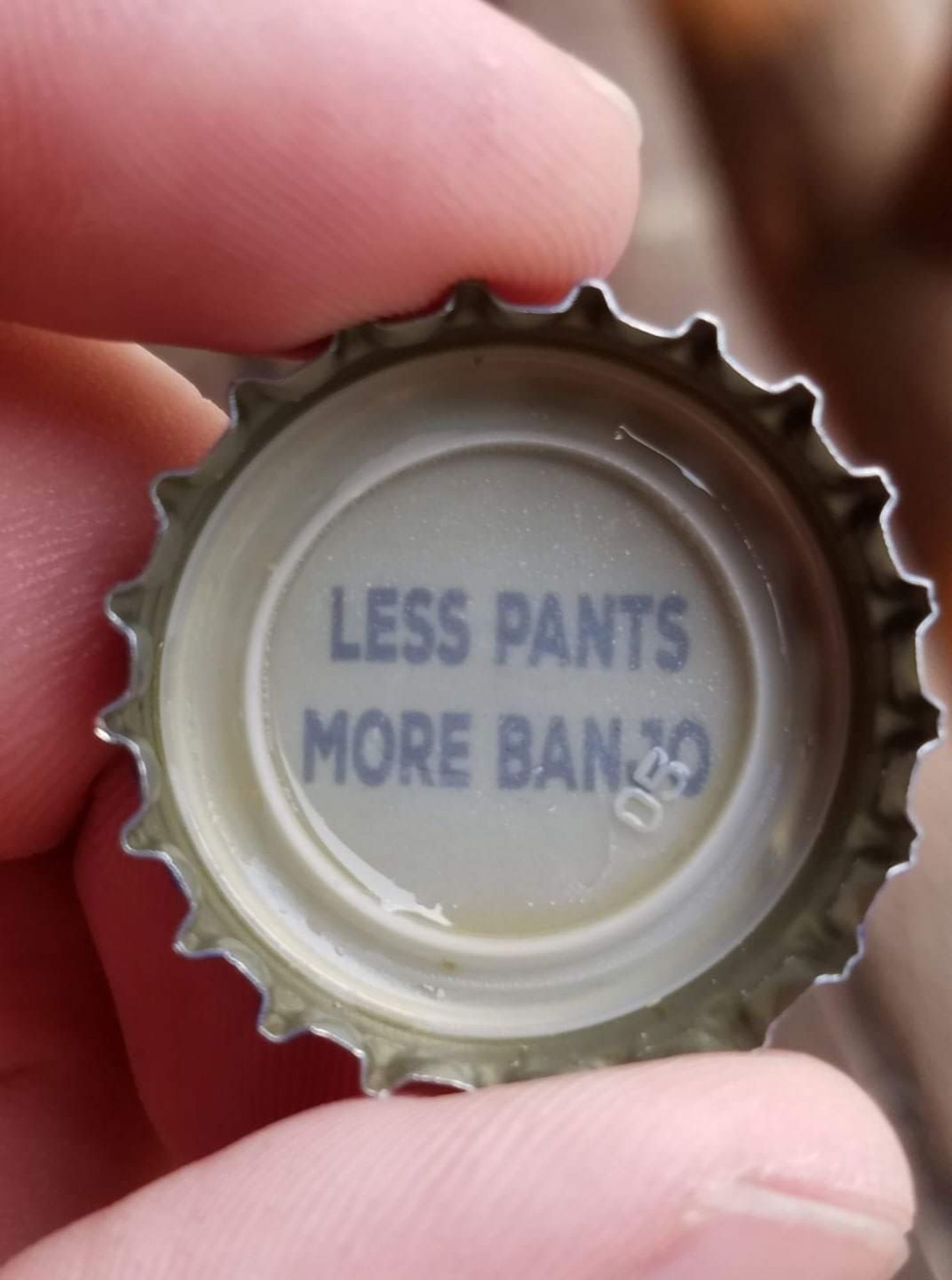 bottle cap with "less pants more banjo" printed inside