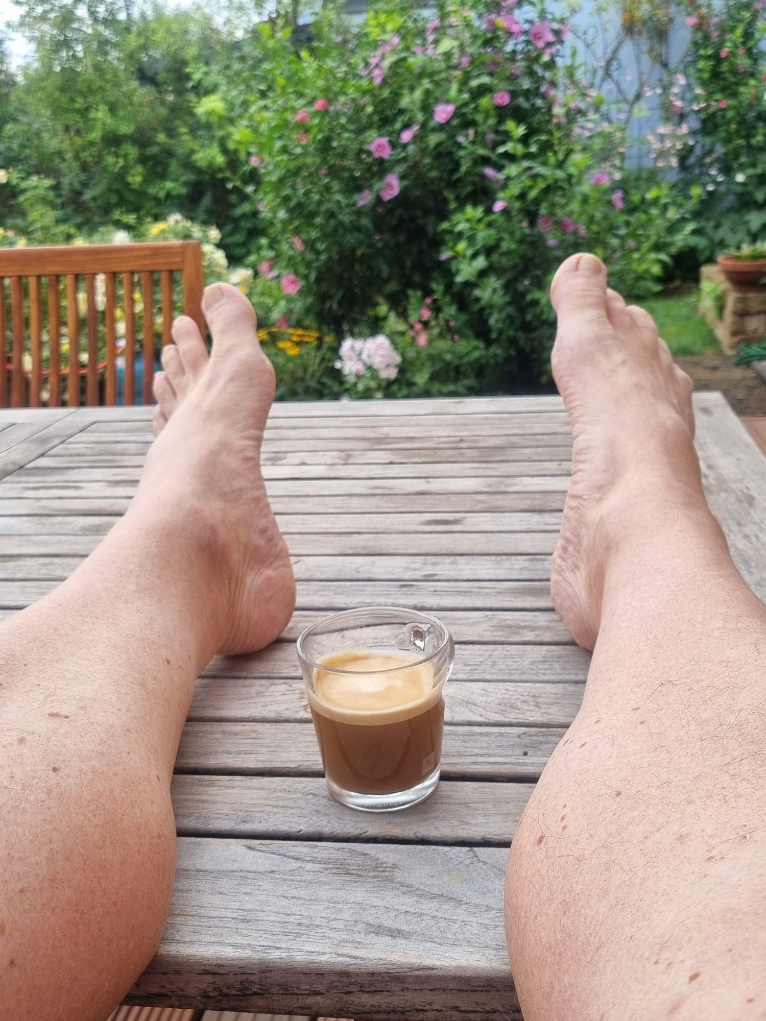 Helis Beine auf dem Terrassentisch. Mit einer Tasse Kaffee.