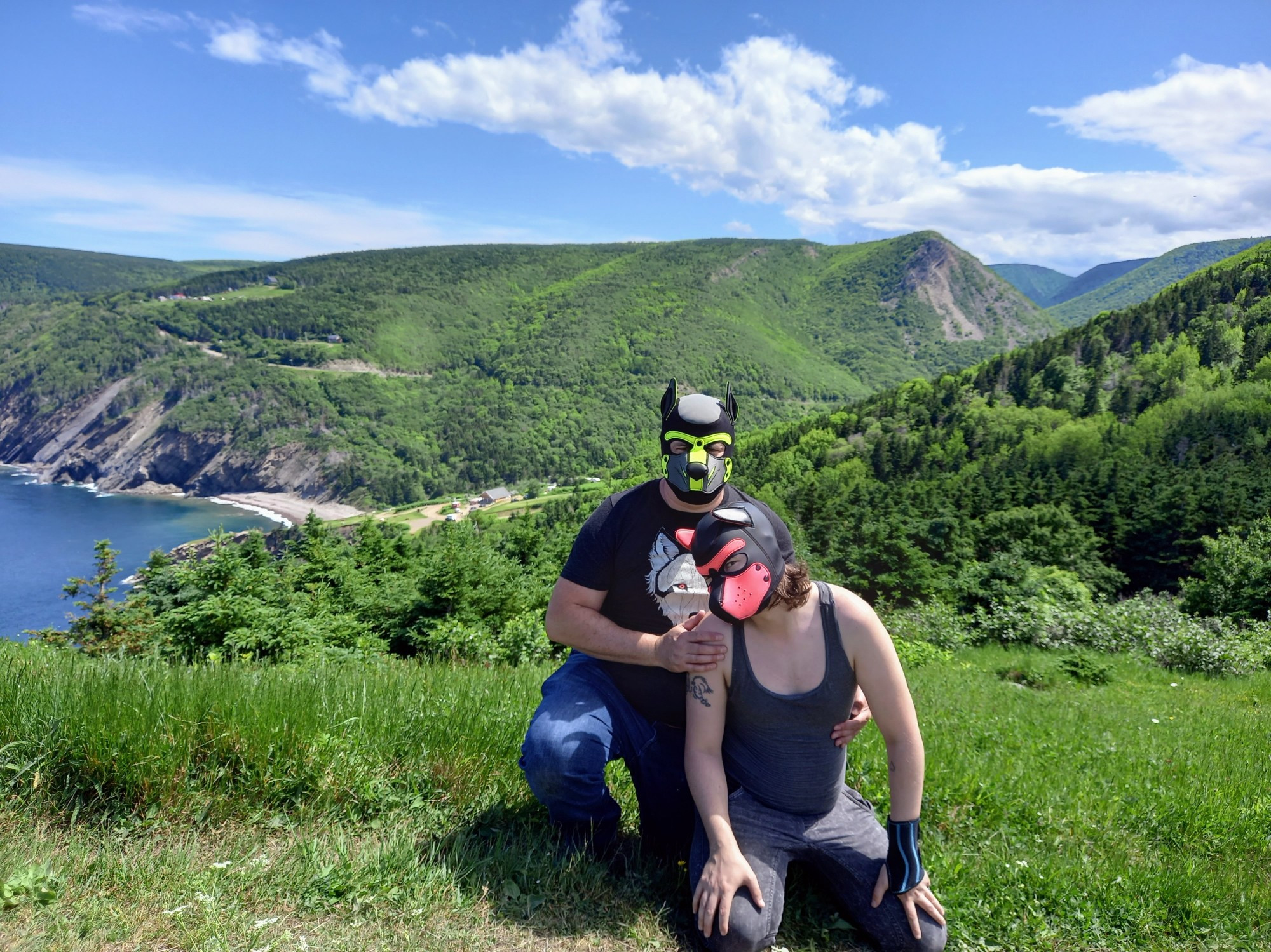 Two human pups kneeling together with breathtaking Cape Breton landscape in background