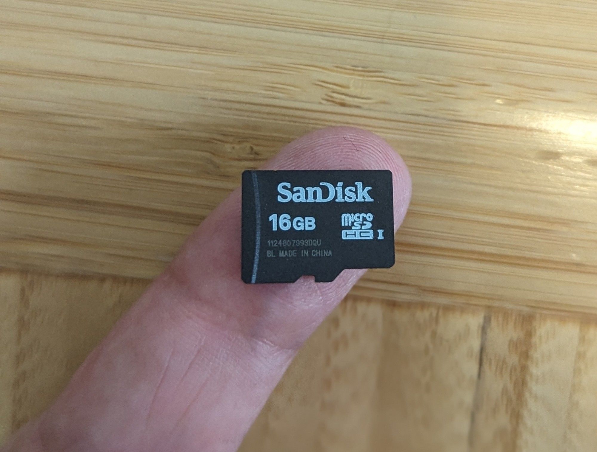 A 16GB microSD card on a fingertip.