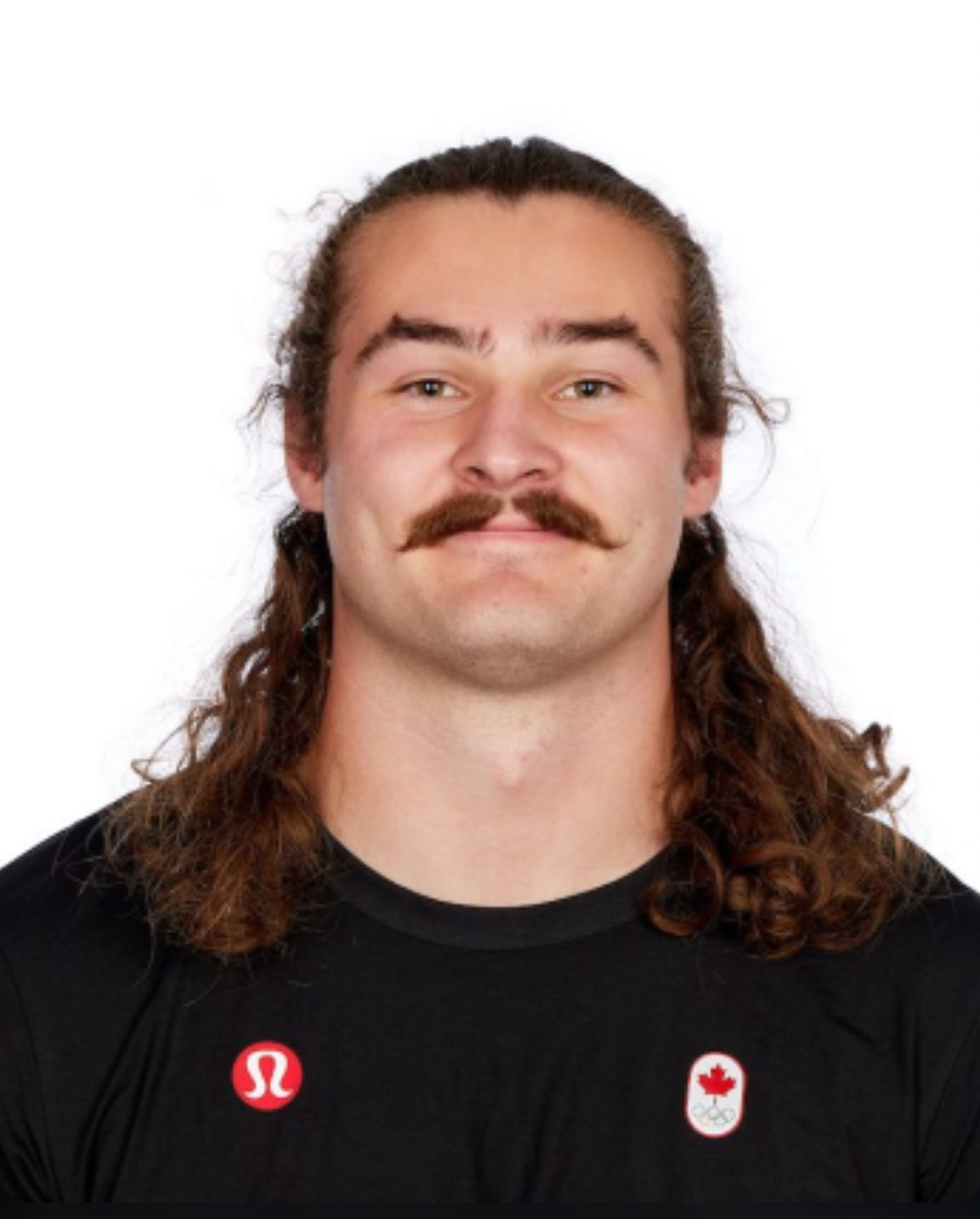 photo of canadian olympic hammer thrower Ethan Katzberg, a white man with a moustache and long hair, wearing a black t shirt with a small canadian olympic logo on it and a lululemon logo, smiling