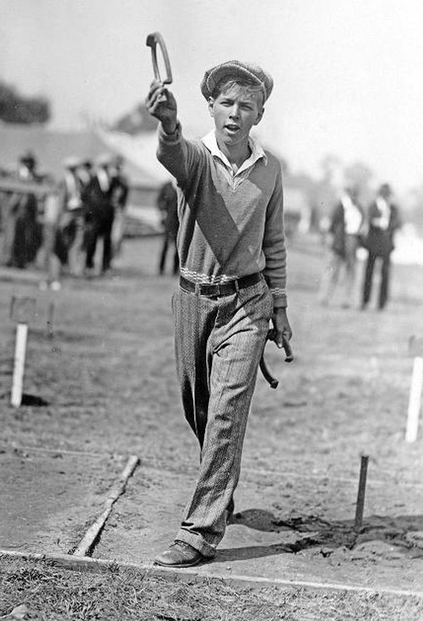 This is a black & white photograph of a teenage boy preparing to toss a horseshoe at a target stake during a contest. He stands in a 3 x 6 foot sandy area surrounding the stake known as the pit. His left foot is carefully positioned behind the foul line, making sure his toss will count. Generally played as a team sport, the rules for scoring are surprisingly nuanced. Reminds me of curling.
     “Champion Horseshoe Pitcher, Merritt Neese of Anderson, Indiana, displays his winning technique at the 1928 State Fair.” Image courtesy of the J.C. Allen and Son Collection, 1926-1952 at the Indiana Historical Society.