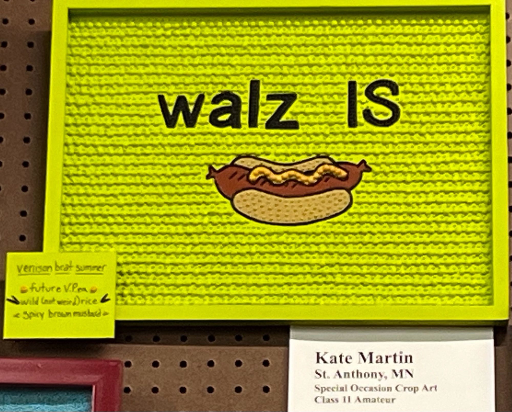 Crop art at the MN State Fair that says “Walz is” and then a picture of a brat.