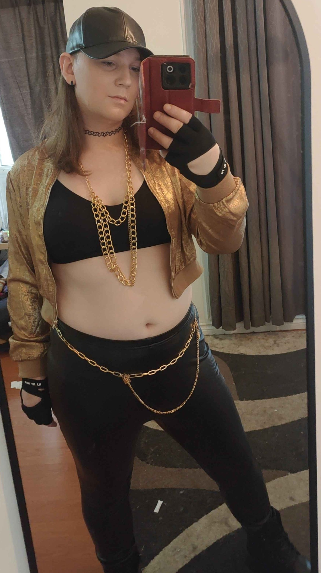 me in a metallic gold coat over a black bra, tight black leather pants, black boots, a leather black cab, gold chains around my neck and waist  