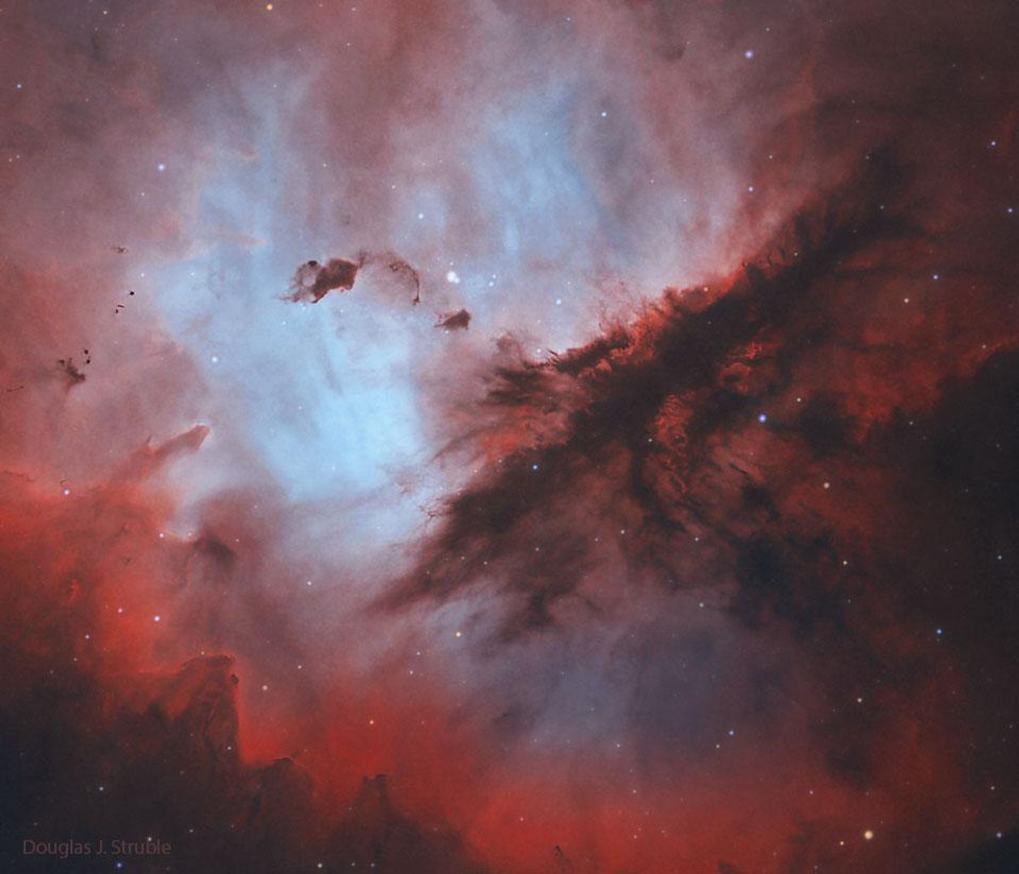 A colorful image of the Pac-Man Nebula (NGC 281), an emission nebula located in the constellation Cassiopeia. The nebula is home to a new open star cluster called IC 1590 and is sculpted by the high energy light and stellar winds from the stars within. The image shows the intricate interstellar dust structures within the nebula. A Bok Globule, a dark cloud of gas and dust, is seen on the upper left of the image. The Bok Globule could collapse to form a new star or stars.