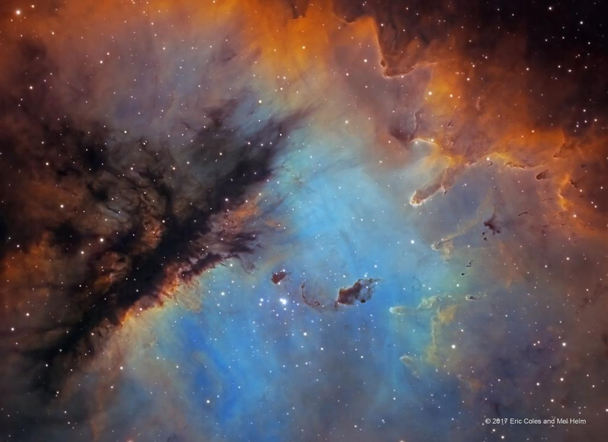 A vibrant image of the Pacman Nebula (NGC 281) in the constellation Cassiopeia. This emission nebula is illuminated by the young, massive stars of open cluster IC 1590, which formed within the nebula. The image shows columns and dense dust globules in silhouette, sculpted by intense winds and radiation from the cluster stars.