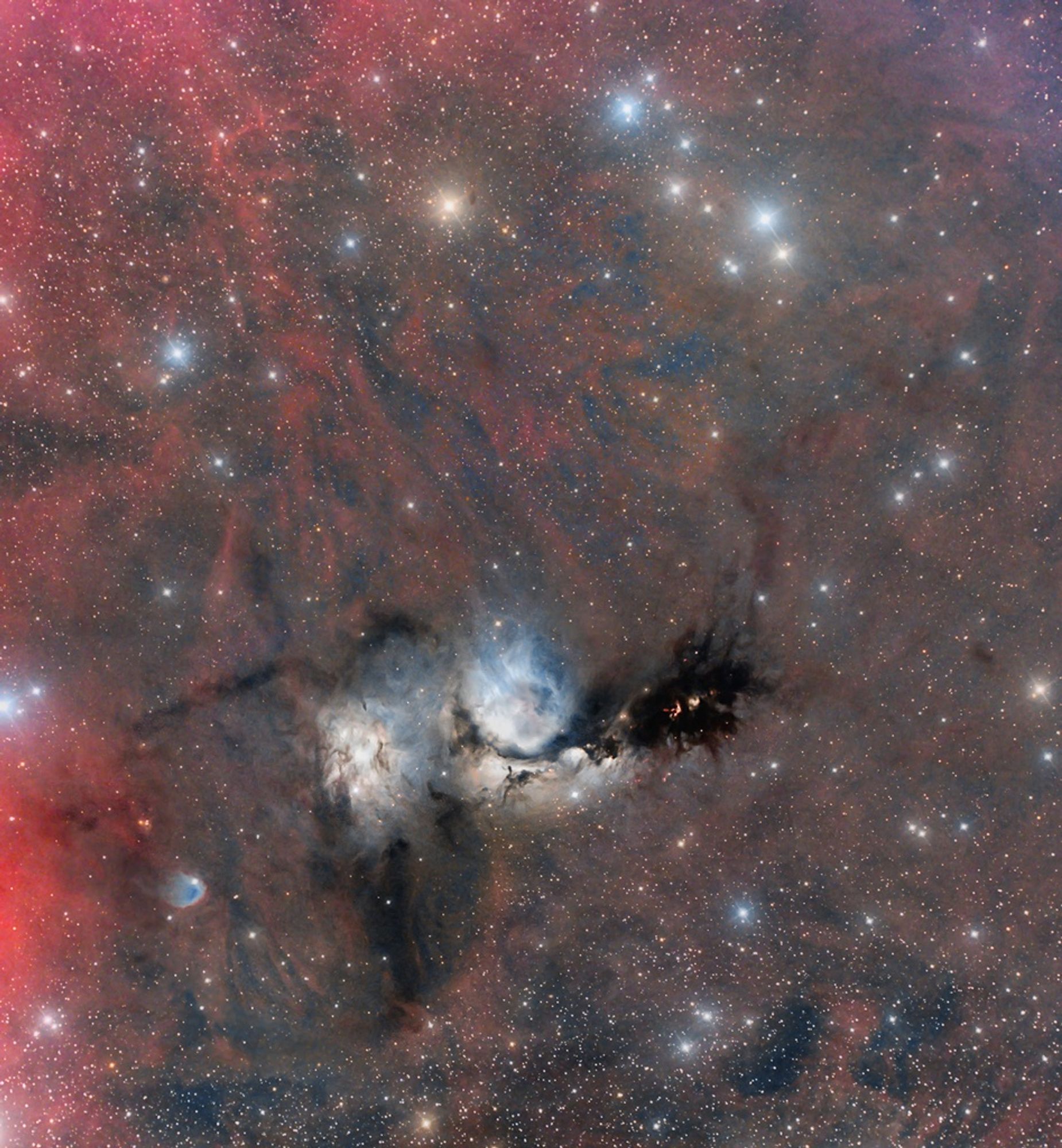 A colorful wide field view of the reflection nebula M78 in the constellation Orion. M78 appears bluish due to the dust reflecting blue light from hot, young stars. The nearby reflection nebula NGC 2071 is also visible, along with dark dust lanes and the faint reddish glow of atomic hydrogen gas.