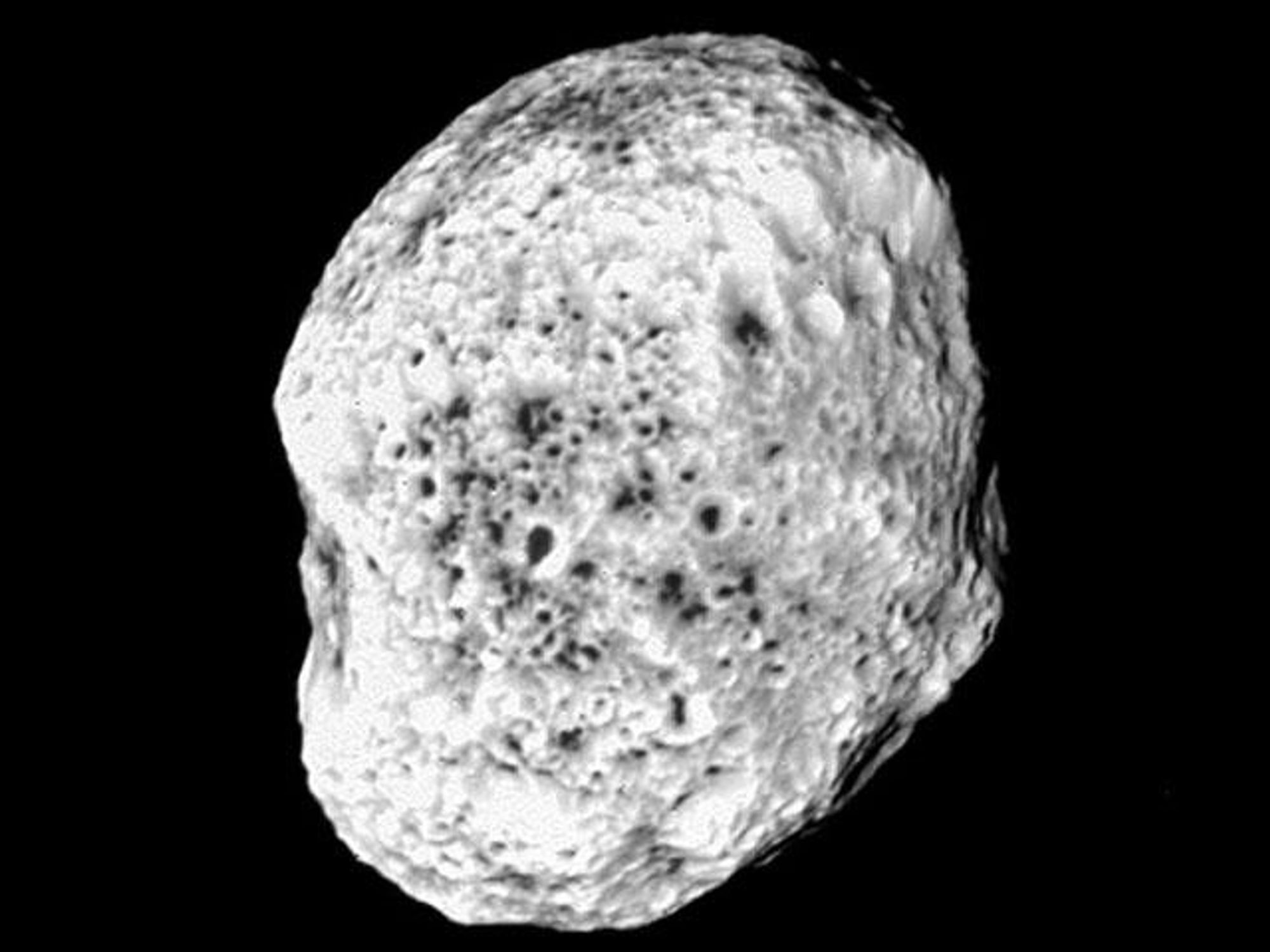 A close-up image of Saturn's moon Hyperion, taken by the Cassini spacecraft. The moon's surface is heavily cratered and has a spongy texture.