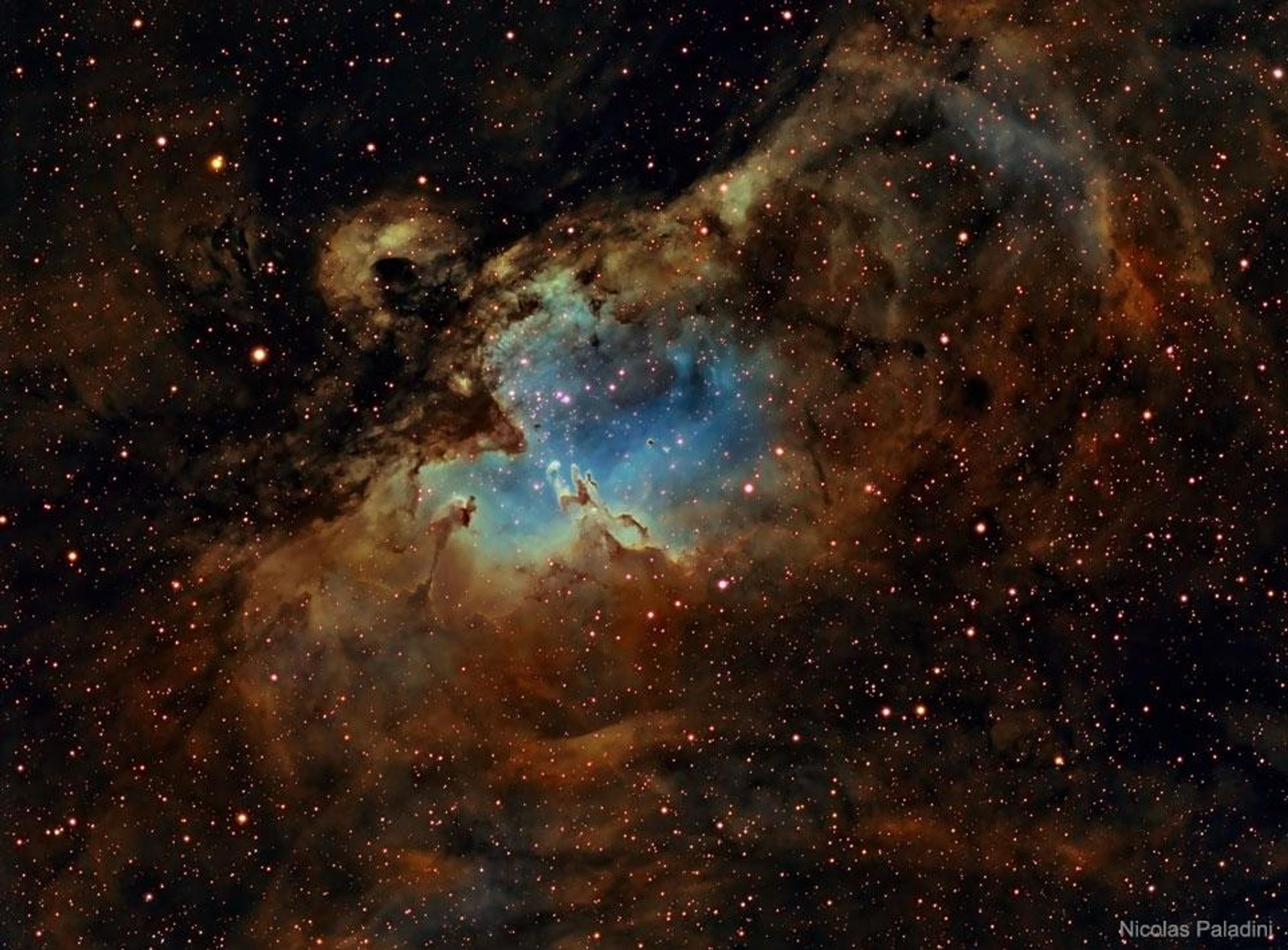 A stunning image of the Eagle Nebula, also known as Messier 16, showing a bright region with a cluster of stars being formed. The image is a combination of three colors emitted by sulfur (red), hydrogen (yellow), and oxygen (blue), creating vibrant colors throughout the nebula.  The Eagle Nebula is located about 6500 light-years away in the constellation Serpens.