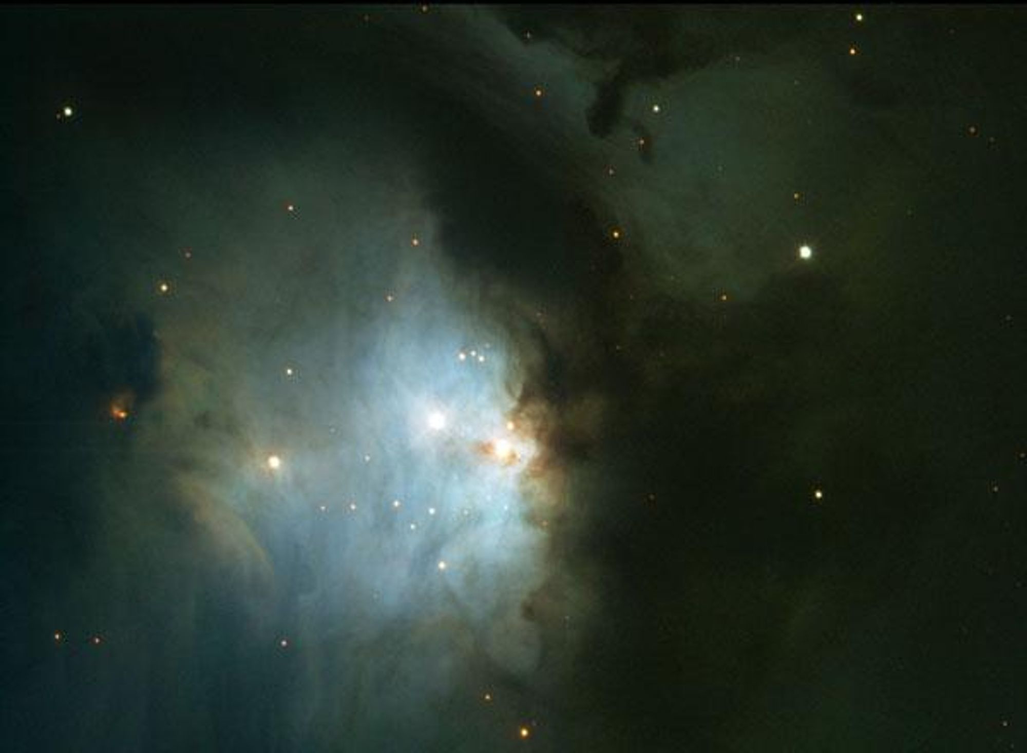 An image of M78, a reflection nebula in the constellation of Orion. It is a bright blue glow with dark dust columns and many stars. M78 is about five light-years across and visible through a small telescope.