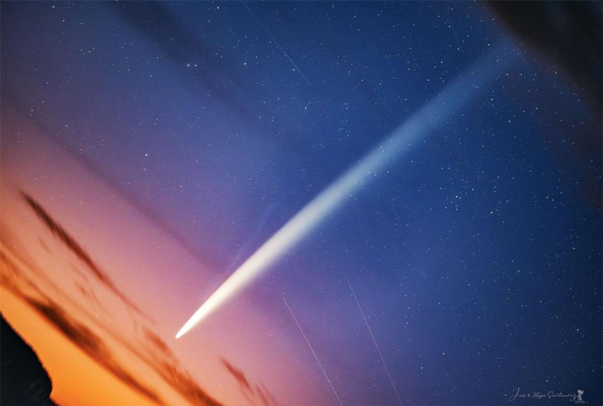 A stunning photograph of Comet Tsuchinshan–ATLAS with both a dust tail and an ion tail, captured just before sunrise from the Andes Mountains in Peru. The bright comet is seen against a star-studded sky, with a pink and purple sunset in the foreground.