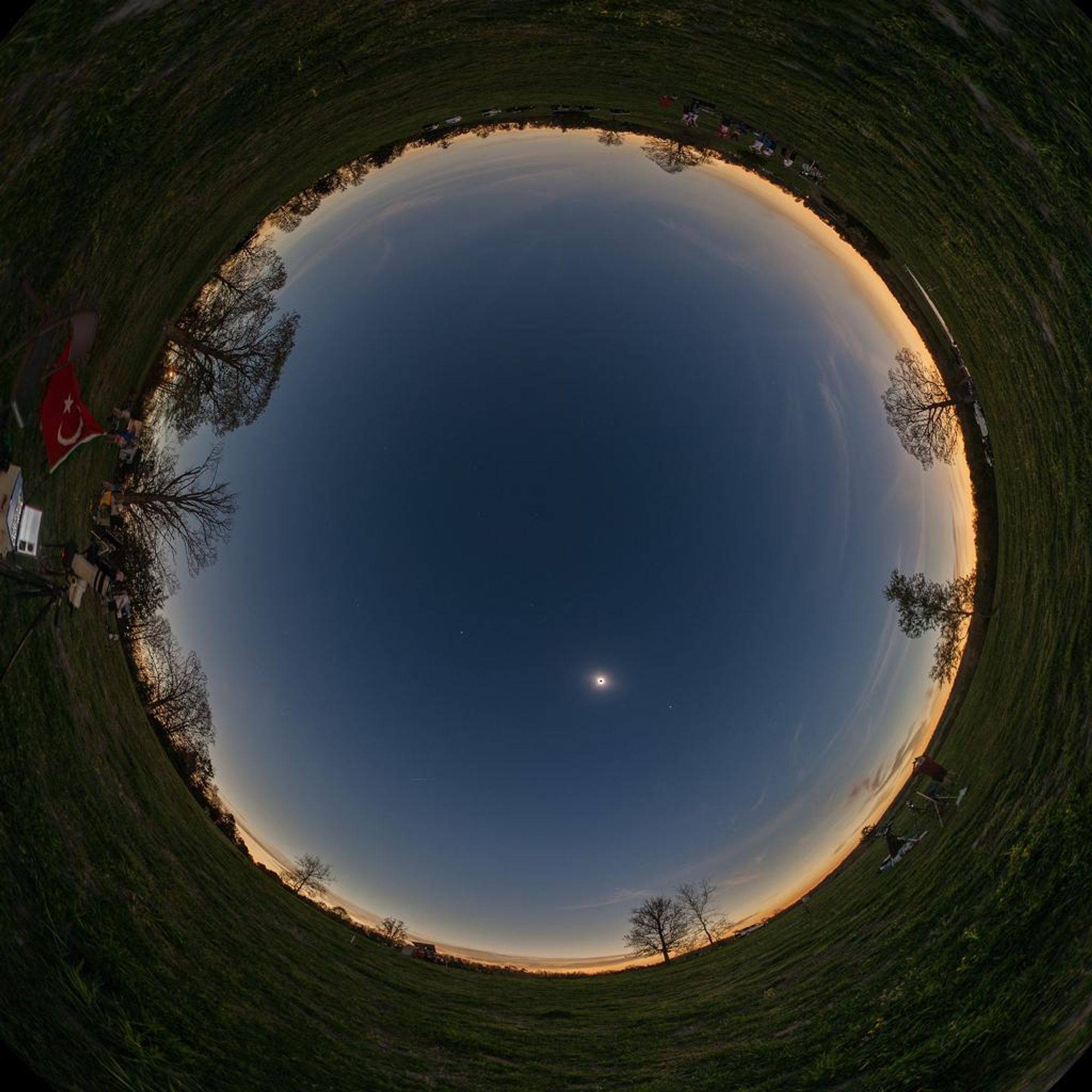 A panoramic view of a total solar eclipse taken from a farm in Shirley, Arkansas. The Moon's shadow is cast over the sky, making it dark, while the horizon is bright with the light of the Sun's corona. Venus and Jupiter can be seen as bright points of light in the sky.