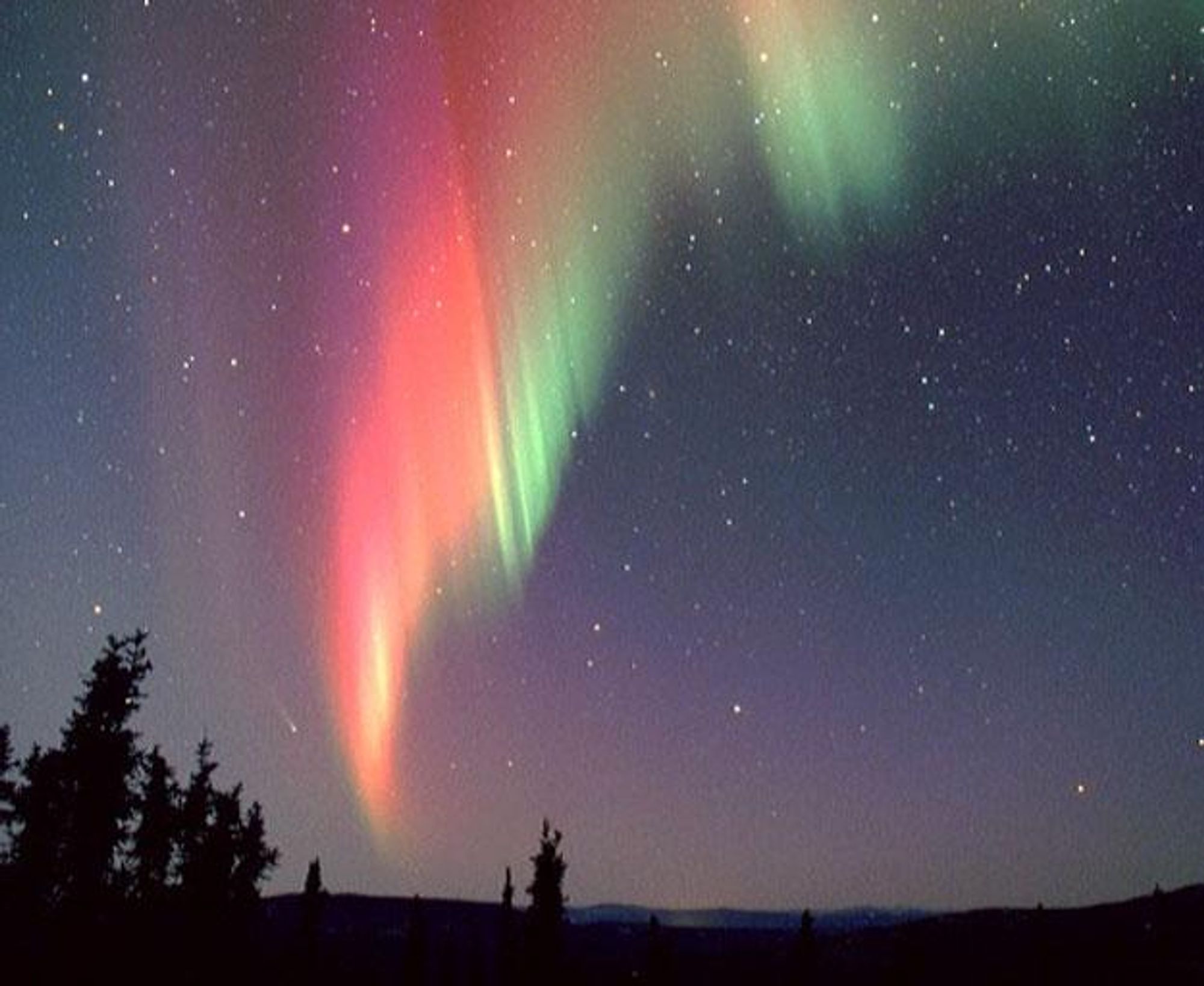 A stunning photograph of the Aurora Borealis flowing across the frozen Alaskan landscape.  In the background, just to the lower left of the aurora, is a faint streak of light - Comet Ikeya-Zhang, the brightest comet of recent years.