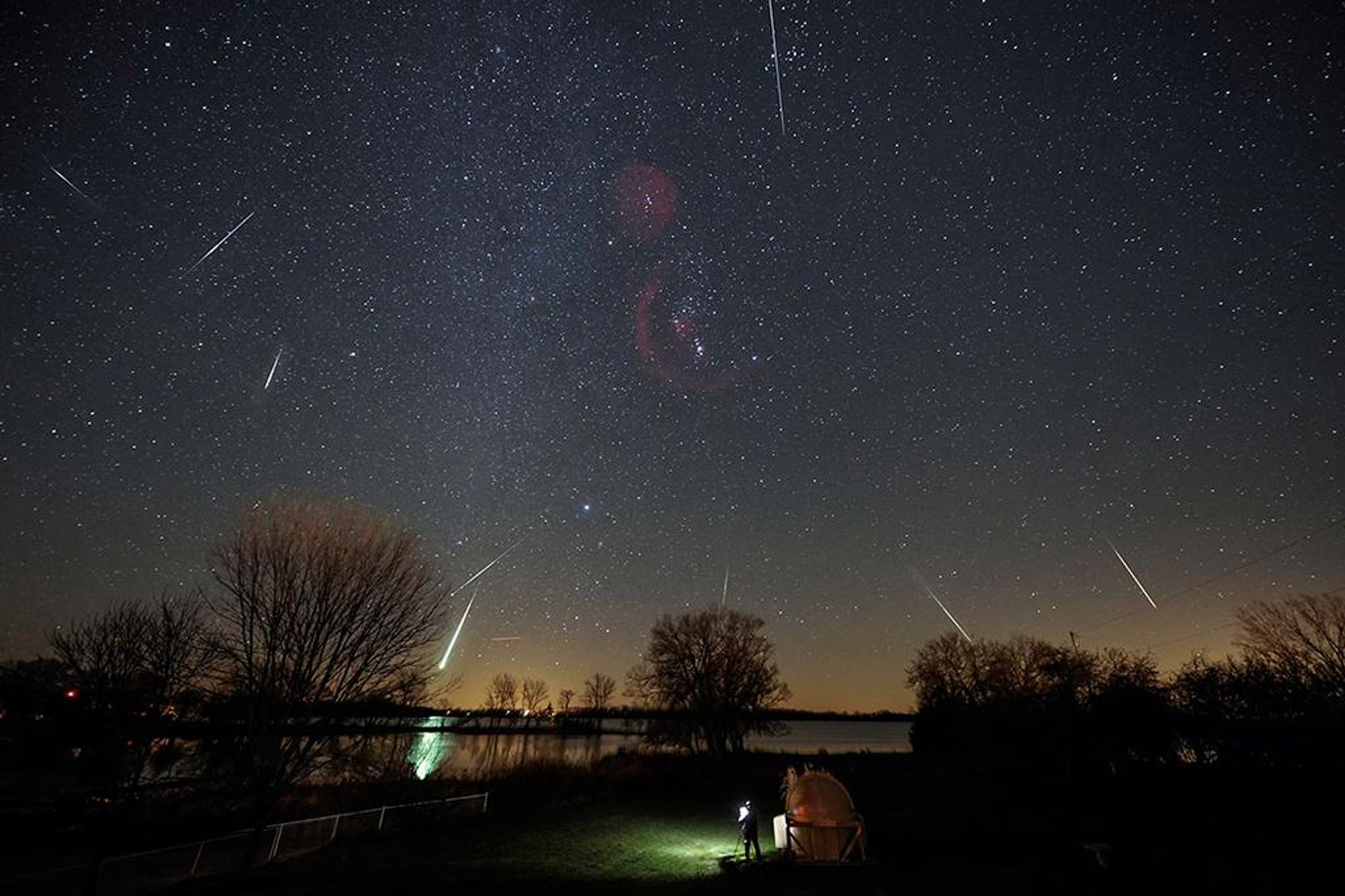 A composite image of the Leonid meteor shower captured from a backyard observatory in Southern Ontario. The image shows multiple meteor trails streaking across the night sky, with the Milky Way visible in the background. The constellation Orion can be seen in the lower right corner of the image.