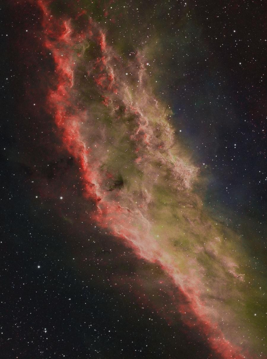 A colorful image of the California Nebula, also known as NGC 1499. This emission nebula is located in the constellation of Perseus and is around 100 light-years long. The nebula is illuminated by the star Xi Persei, which is located just outside the right edge of the image.  The image shows the nebula in red, green, and blue, which represent sulfur, hydrogen, and oxygen, respectively.  The nebula is shaped like the state of California.