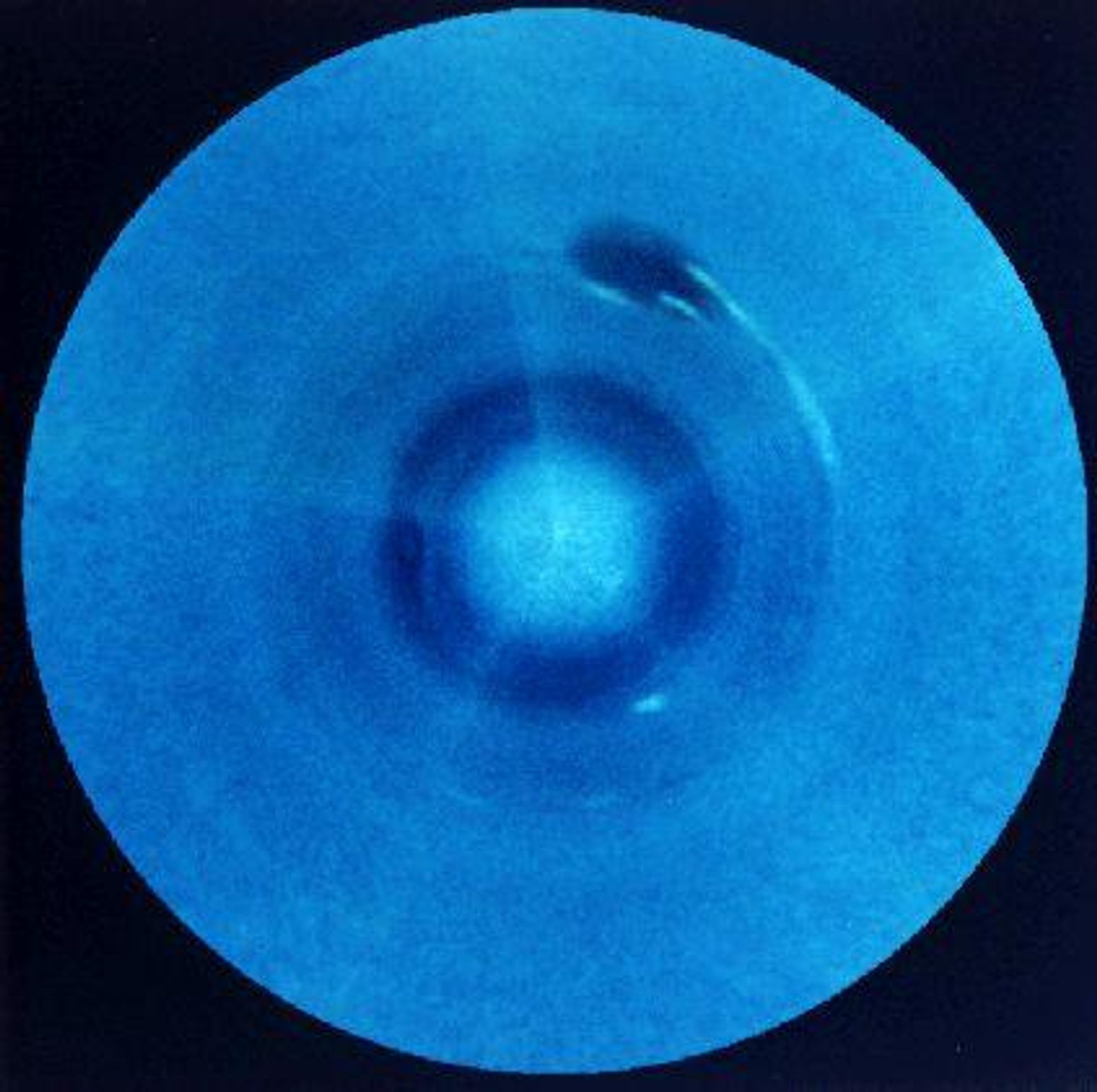 A mosaic of 5 Voyager 2 images showing the southern hemisphere of Neptune, a blue gas giant planet. The image shows cloud bands, and a dark, Earth-sized storm called the "Great Dark Spot" with trailing white clouds.  The Great Dark Spot is located at about 22 degrees southern latitude.  The distance from the Great Dark Spot feature to Neptune's South Pole (image center) is about 17,000 miles.  This image was taken in 1989 by Voyager 2, which had launched 12 years earlier in 1977.