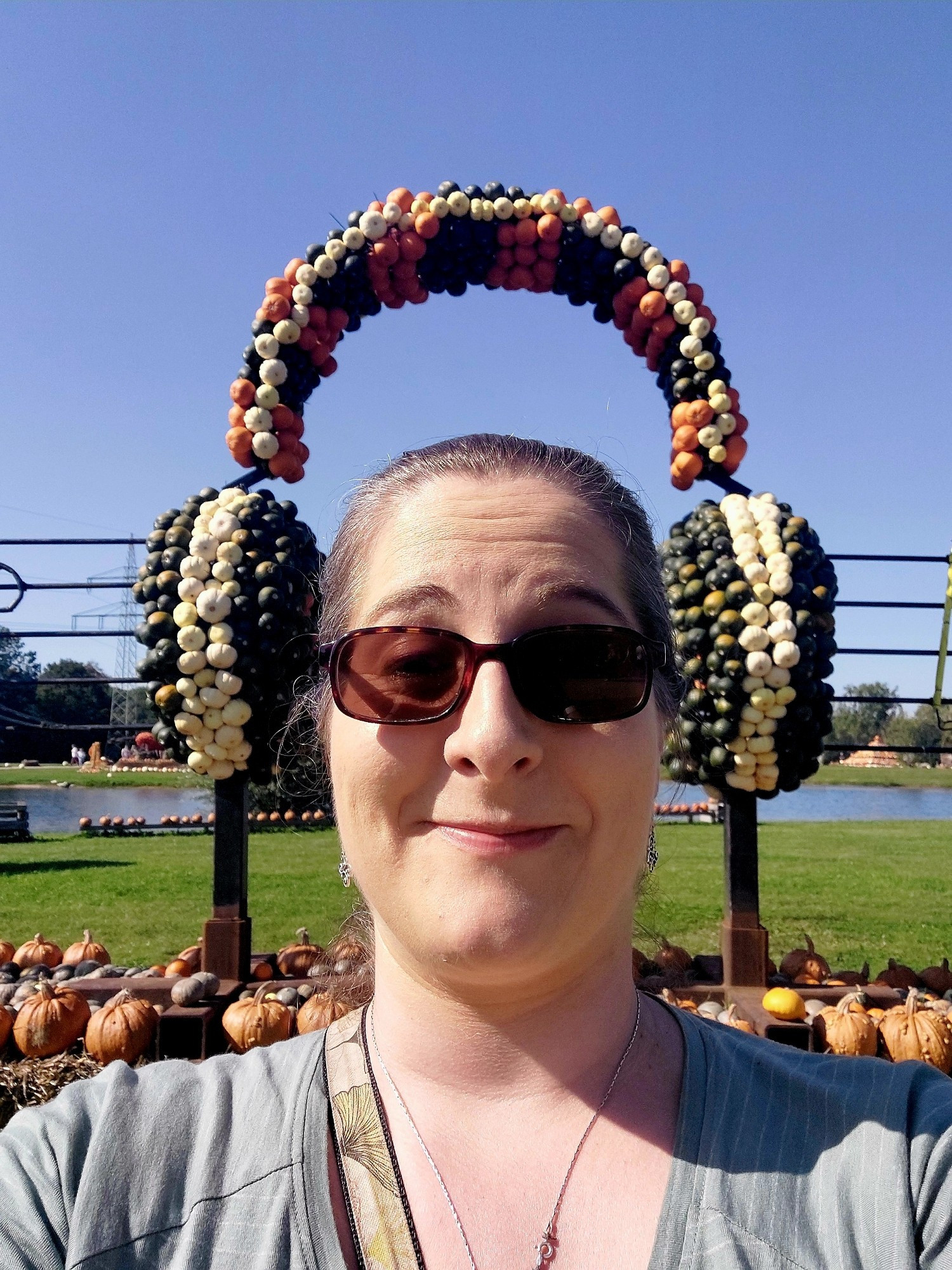 Photo of me with headphones made of pumpkins. The angle makes it look like I am wearing the pumpkin headphones