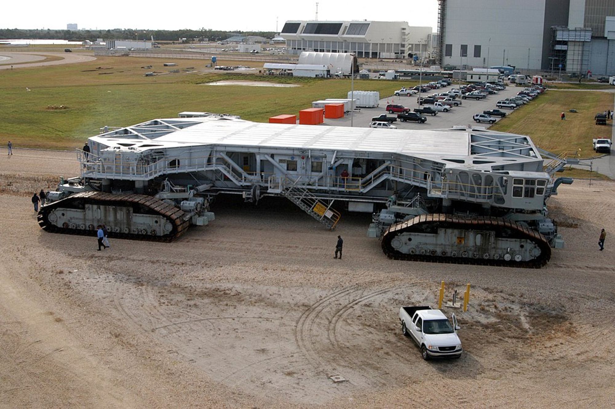 crawler transporter with people and truck nearby for scale