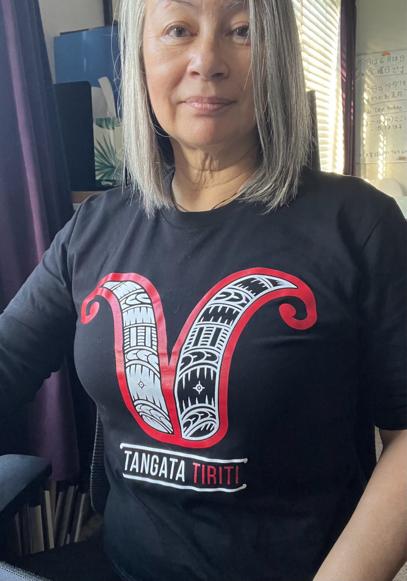 Image shows NinjaKitty wearing a black tee-shirt with the words and design for Tangata Tiriti (treaty partner)