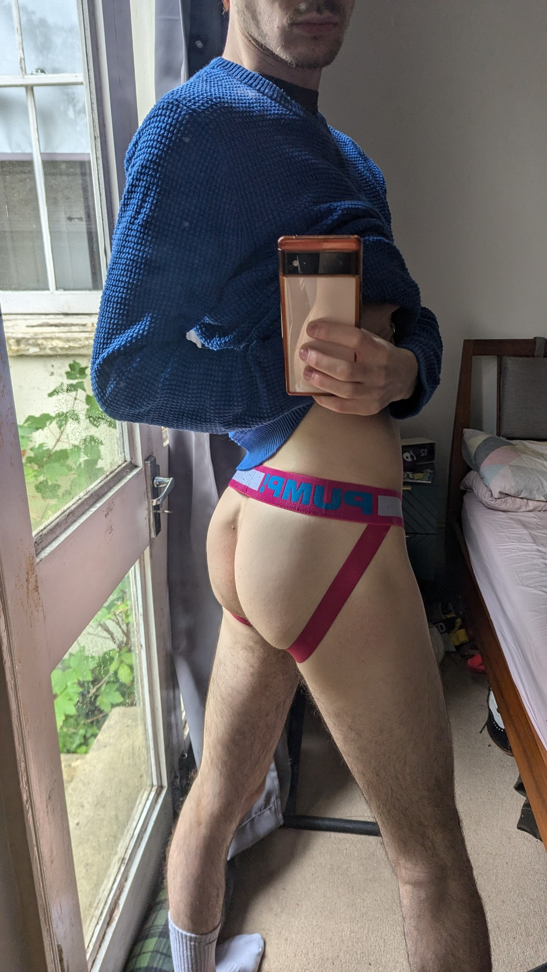 4 photos of me - this is a mirror selfie, holding up a blur jumper to show off my ass in a bright pink jockstrap 