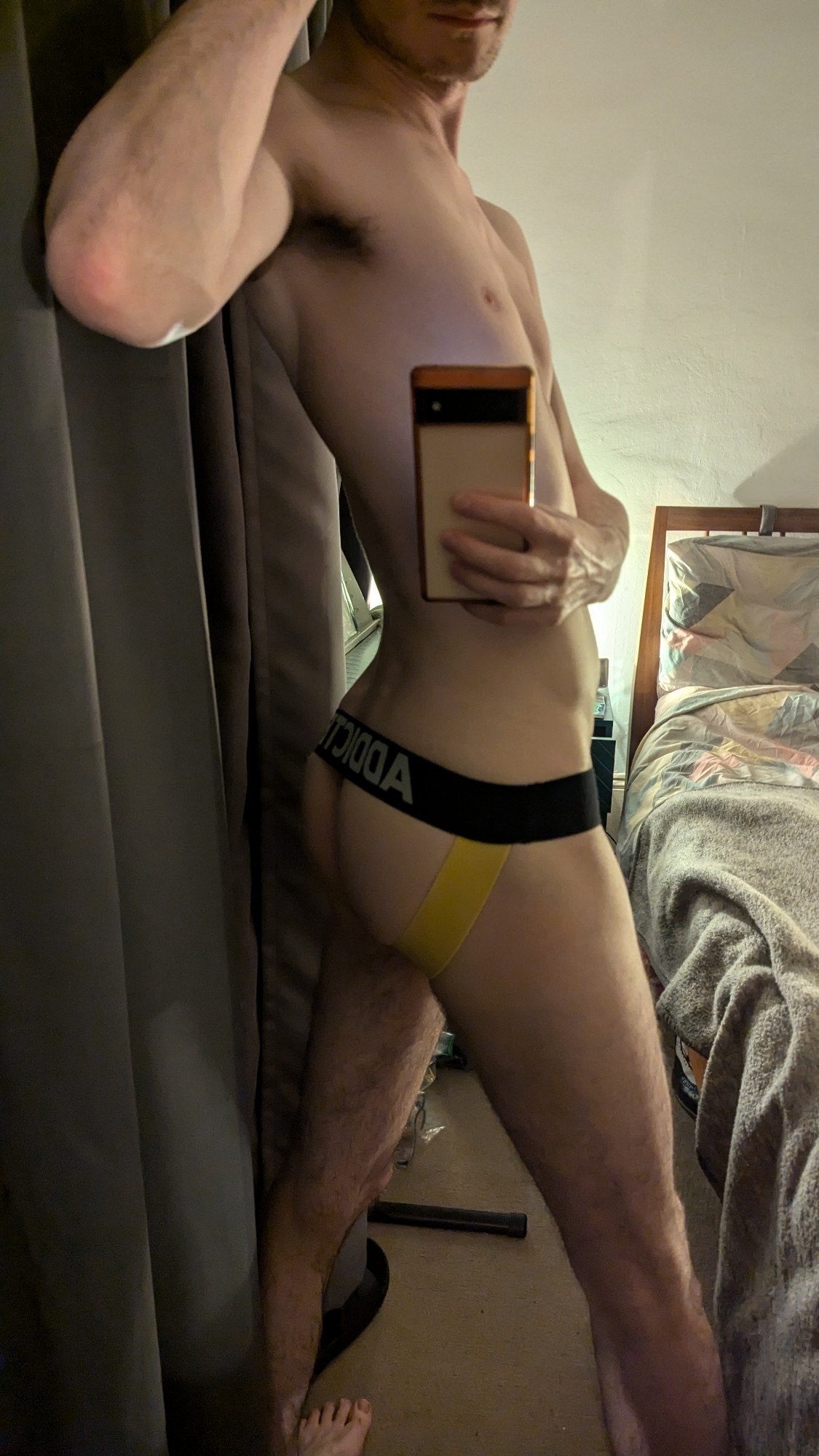 low light mirror selfie of my ass in a black and yellow jockstrap