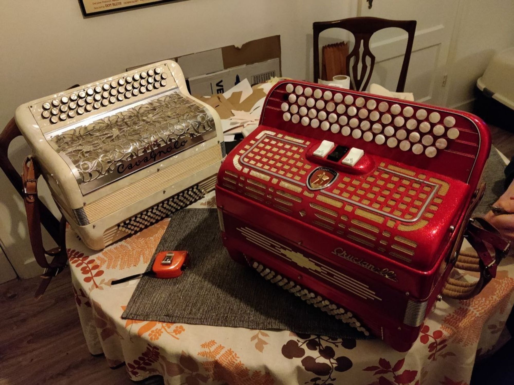 Two small chromatic button accordions on a table. A French cavagnolo on the left and an Italian crucianelli on the right. Both compact models from the 70s.