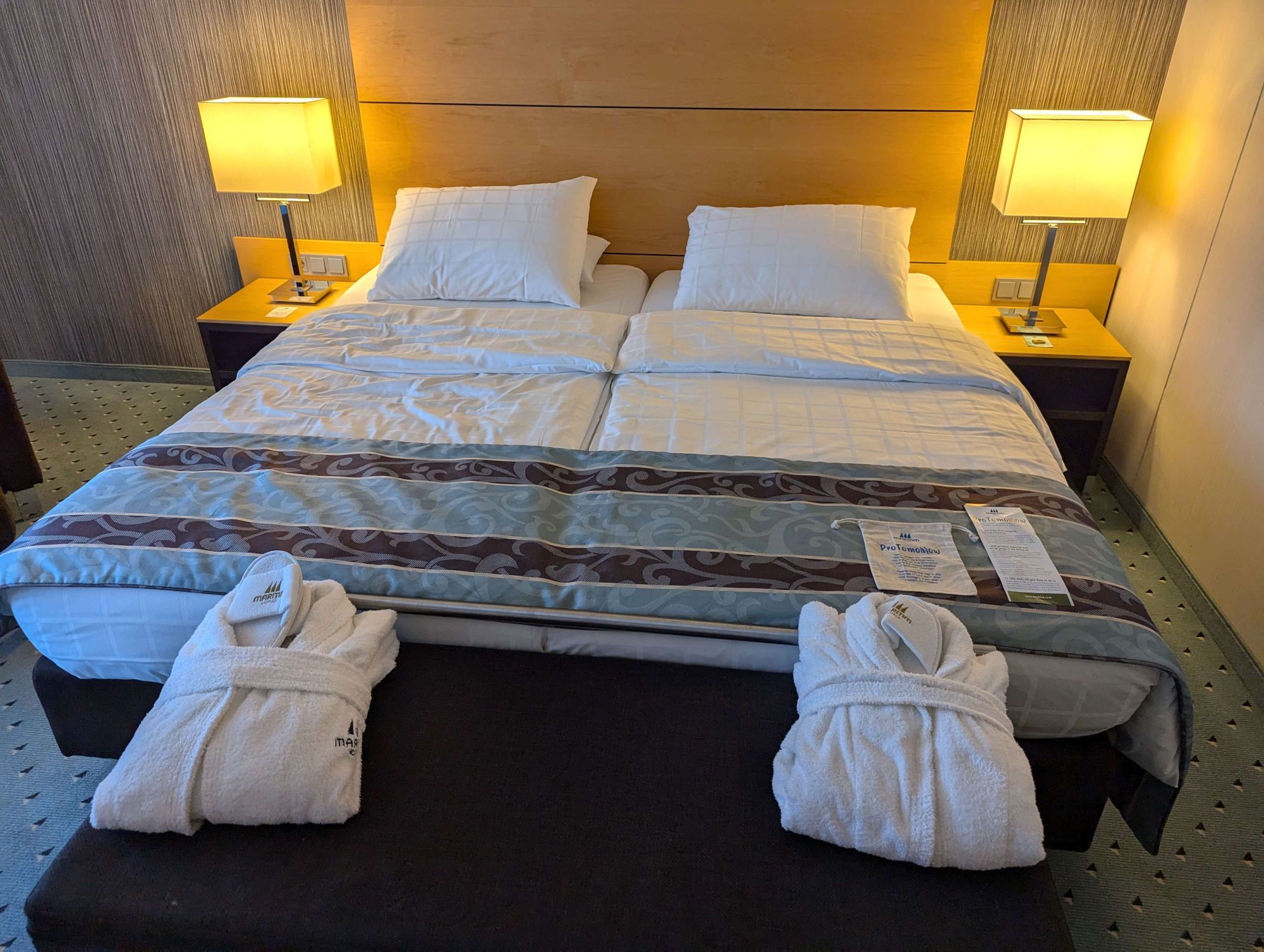 Hotelzimmer mit Grossem Doppelbett. Im Vordergrund liegen 2 Bademäntel