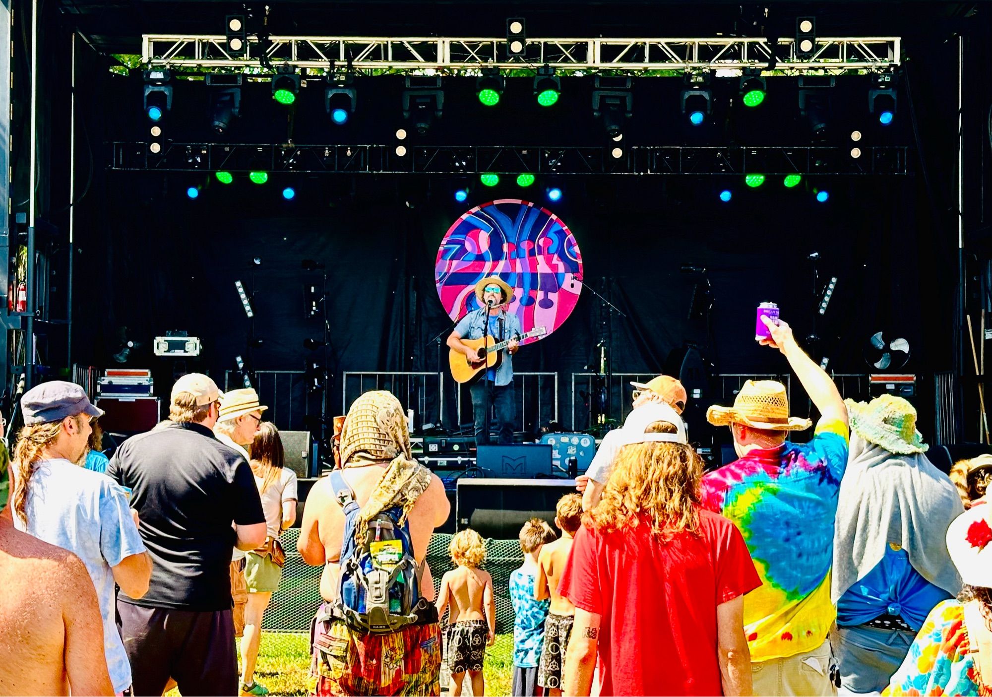 Chicago Farmer singing and playing guitar in front of a sunlit crowd.