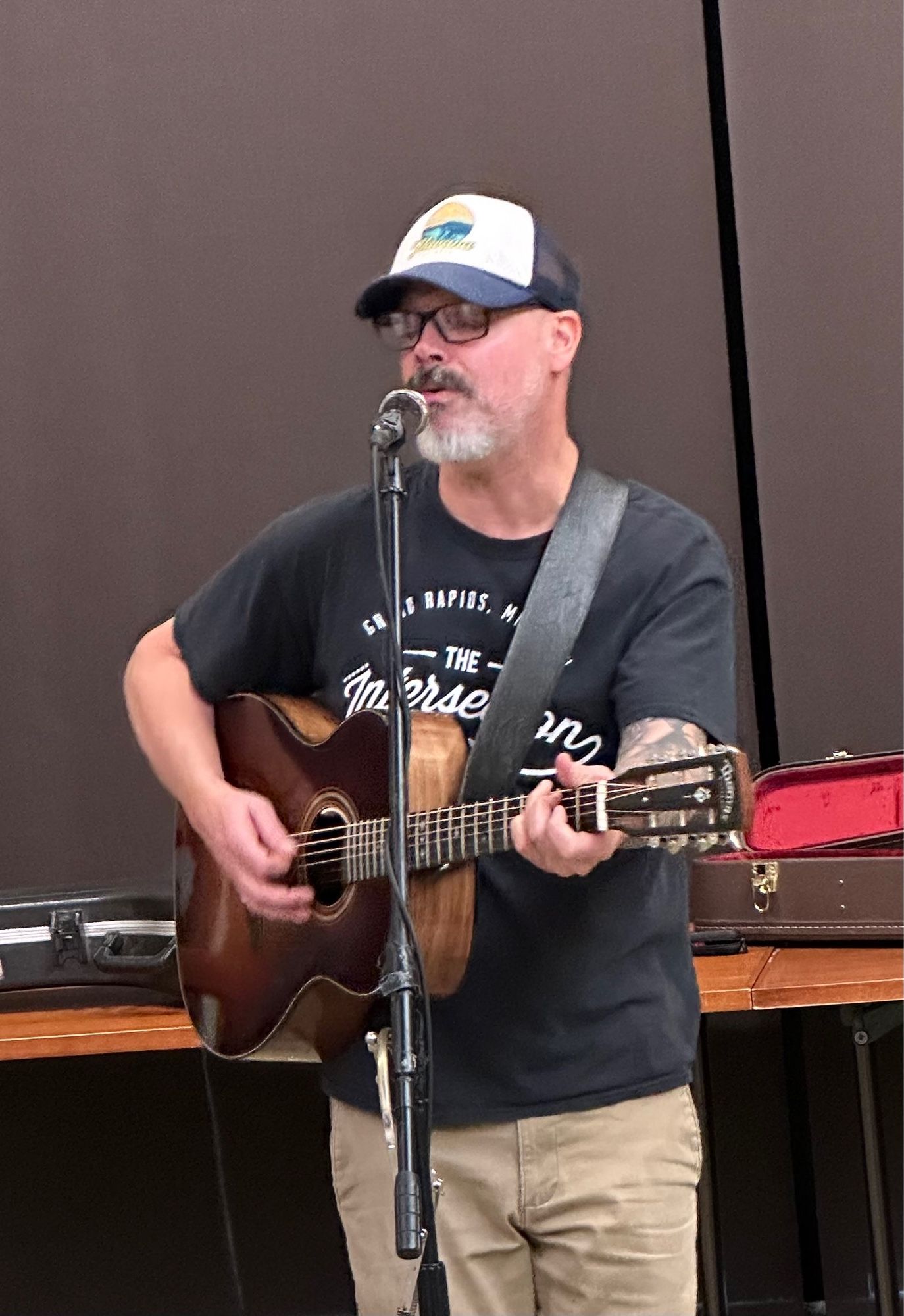 Medium shot of Edward David Anderson playing guitar and singing.