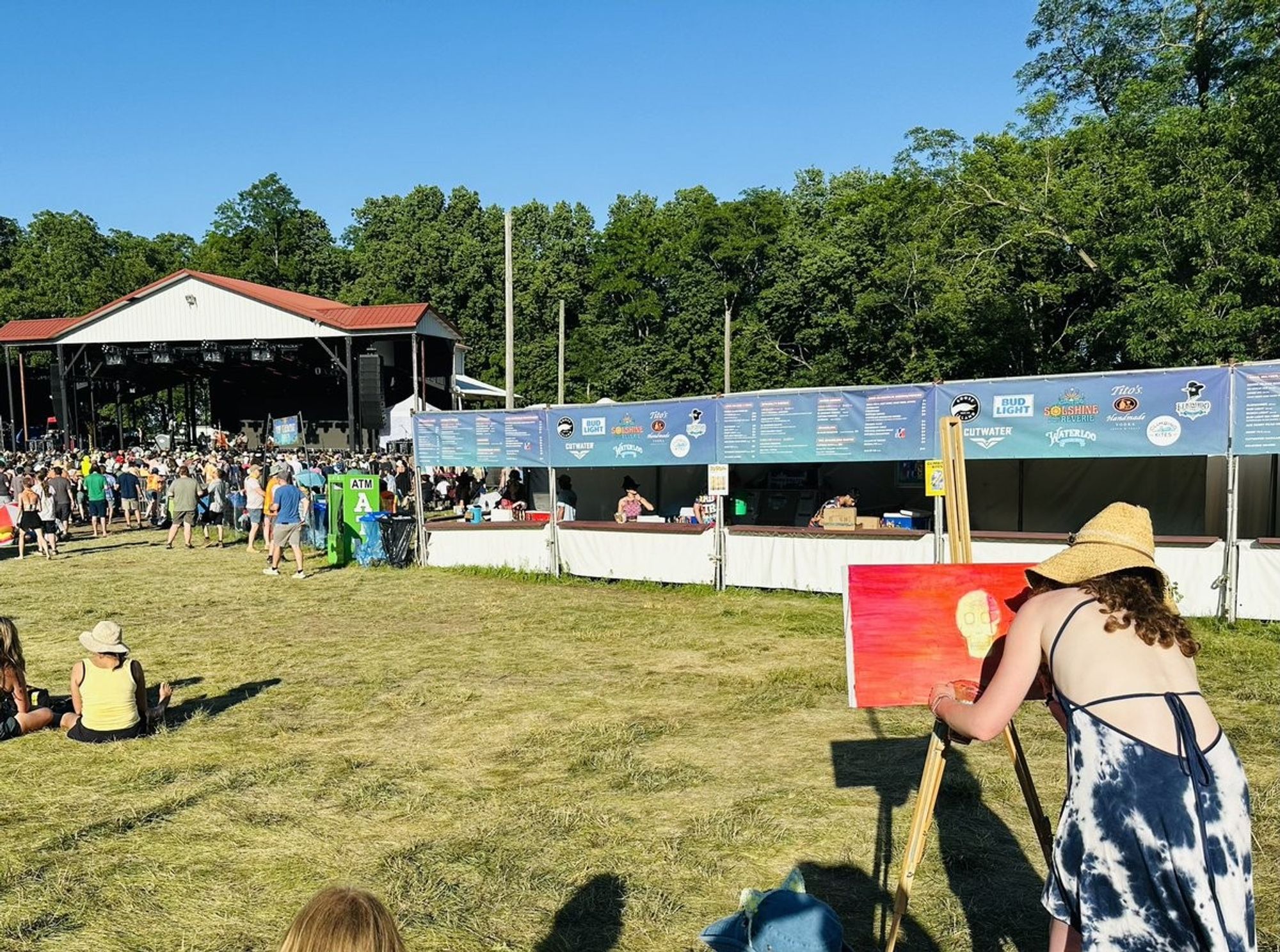 Woman painting on a canvas.  the stage is in the far left background.