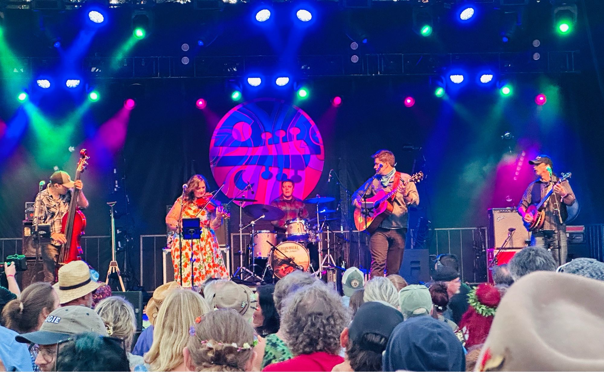 Five piece band, from left: man playing upright bass, woman on fiddle, man on drums, man on guitar, and man on banjo.