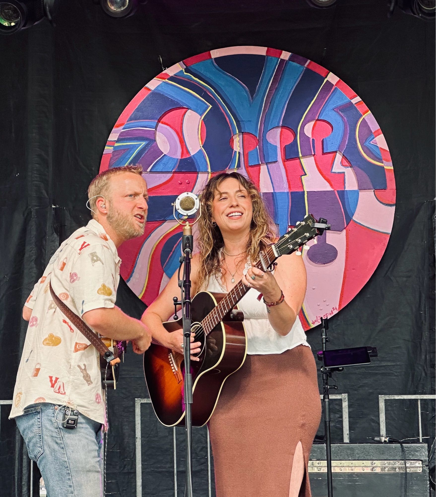 From left: a man playing a mandolin and singing, a woman playing guitar and singing.