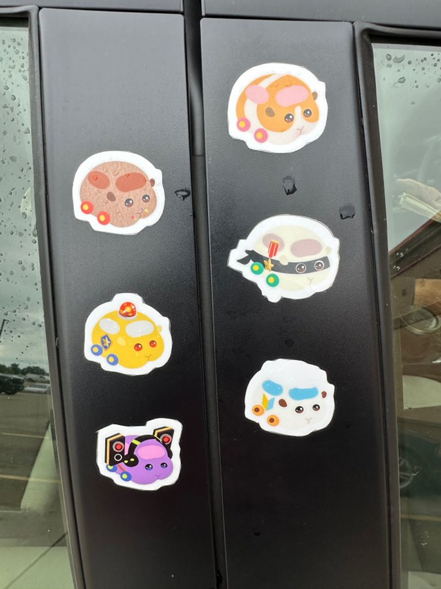 Close up of the six stickers on the passenger's side doorframe: various guinea pigs as automobiles.