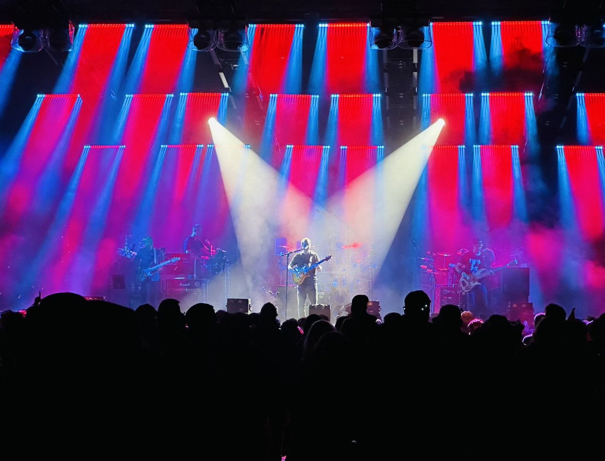 Entire band with lead guitarist centered in two spotlights