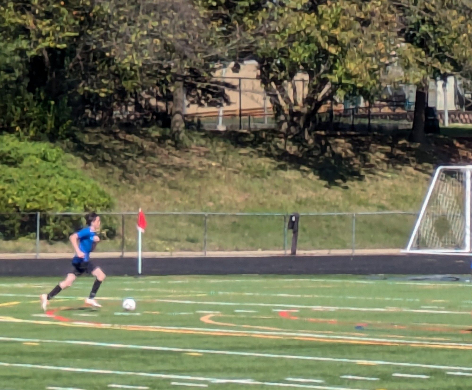 Boy in blue shirt and black shorts running toward a soccer ball.