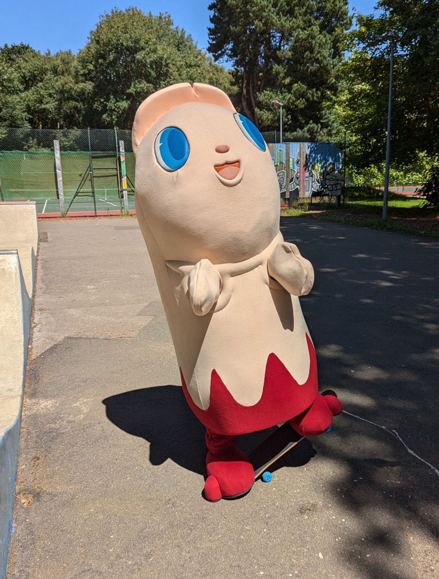 A bloody severed finger mascot walks in front of some trees.