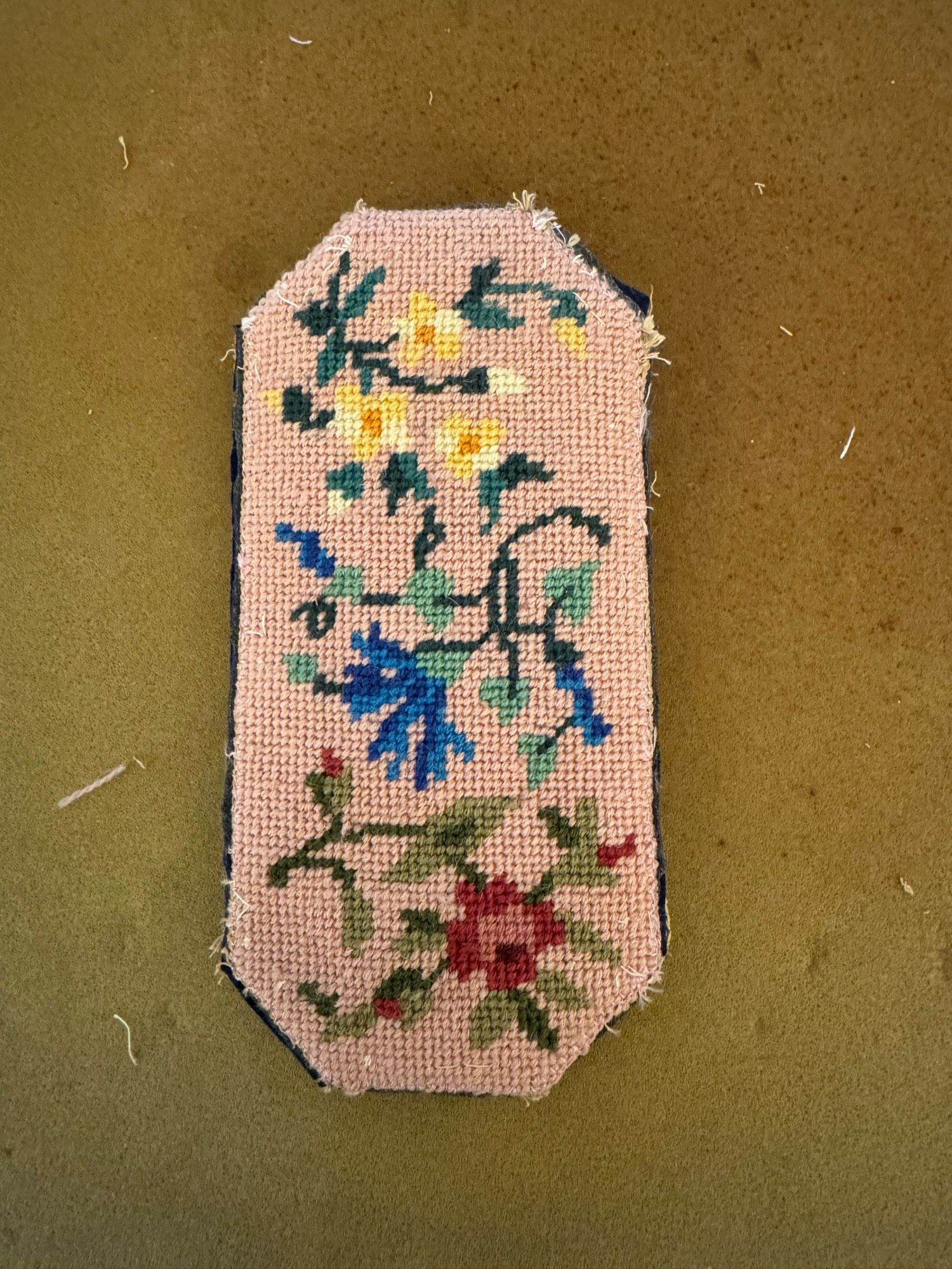 Other side of the pink floral needlepointed glasses case on a beige background.