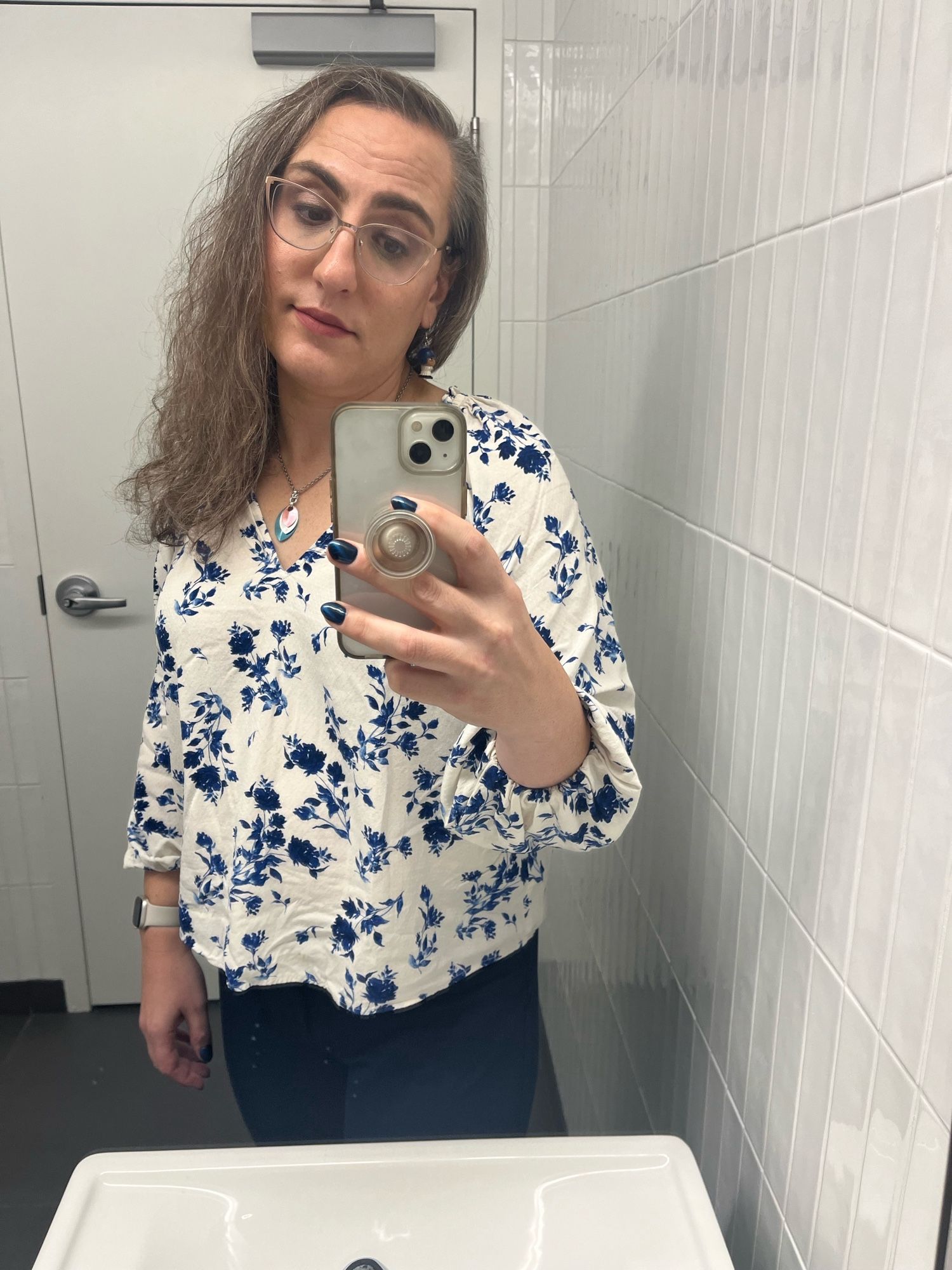 Me, Dawn, taking a bathroom selfie in a white blouse with blue flowers on it