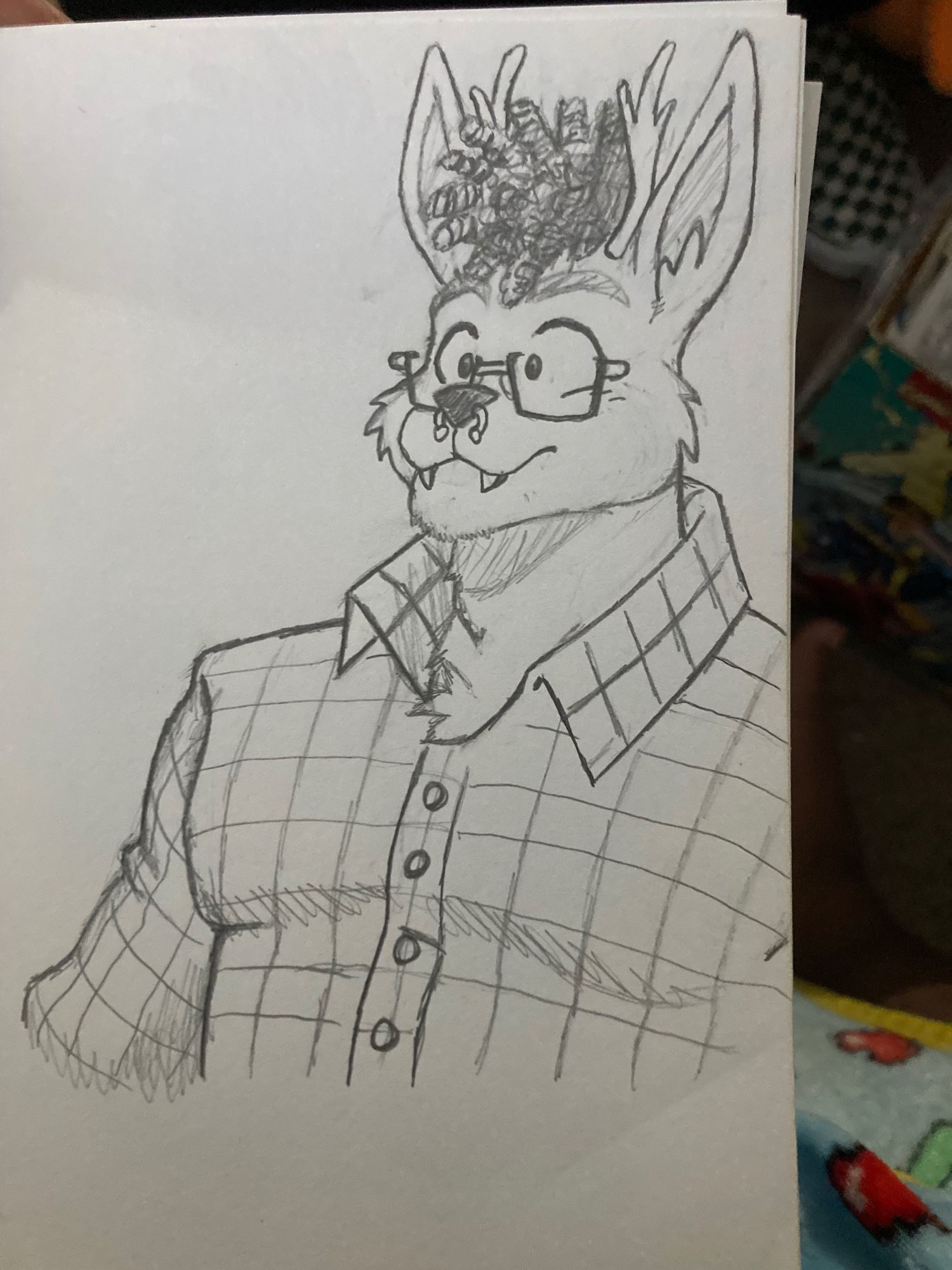 Photo of a sketched chubby Jackalope from the chest to head smiling in a plaid shirt, with short curly hair and glasses