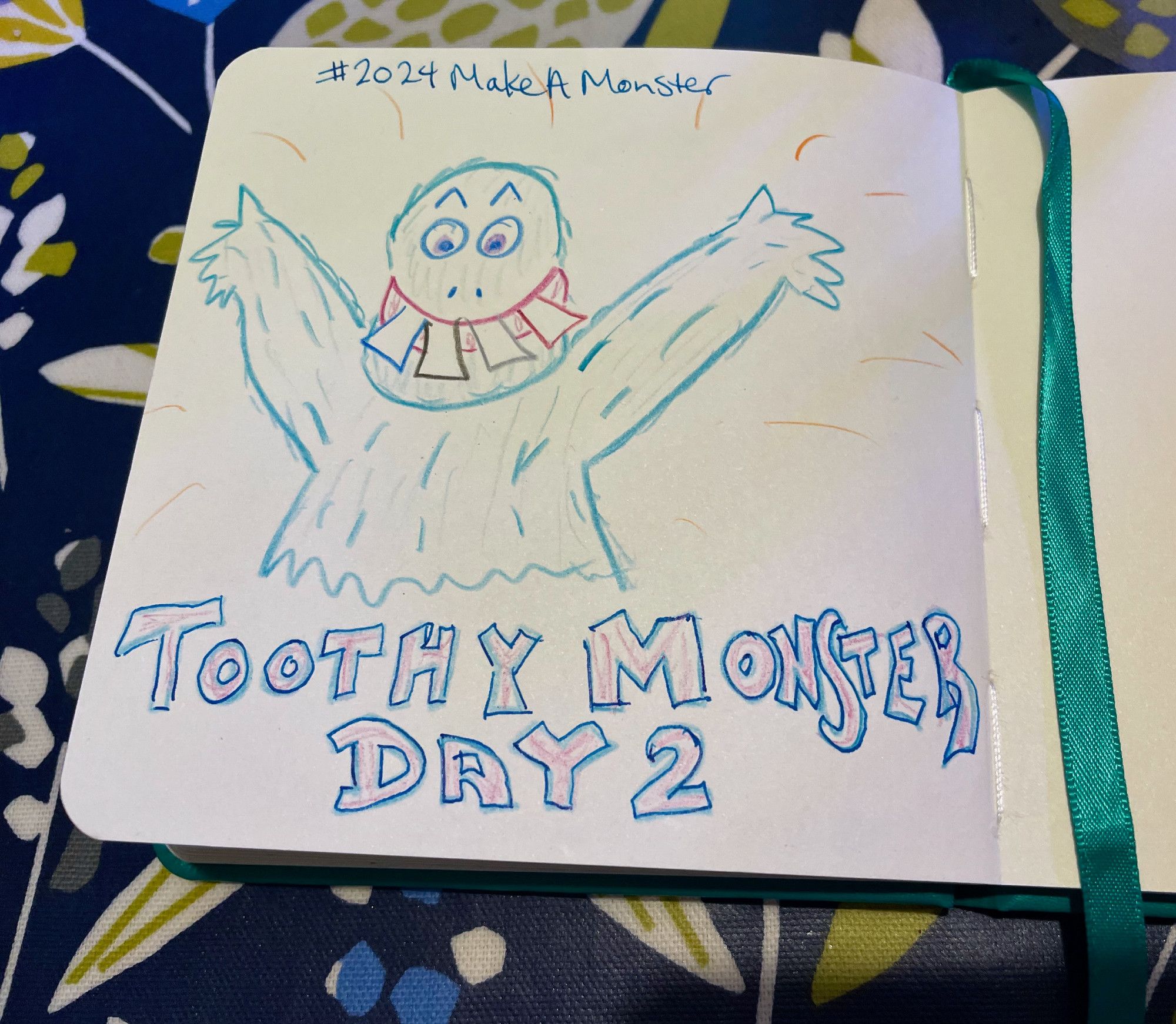 On a small, square sketchpad, Steph has used colored pencils to draw a delighted-with-itself furry monster with four absolutely enormous front teeth sticking out of its mouth as it grins and flings its furry arms into the air, showing itself off to the world. The text (in fountain pen ink) reads #2024MakeAMonster Toothy Monster Day 2.