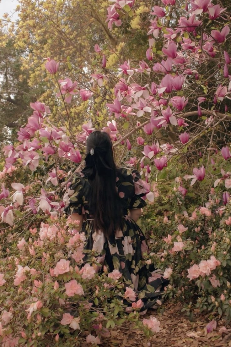 A girl in a black floral dress, surrounded by magnolias.