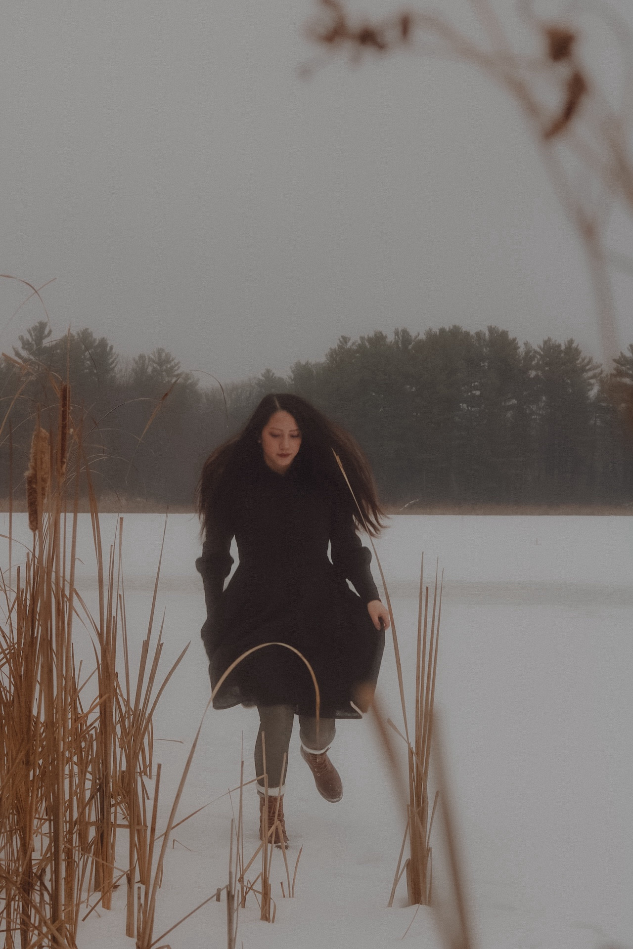 A girl in a black dress, moving on a snowy frozen lake.