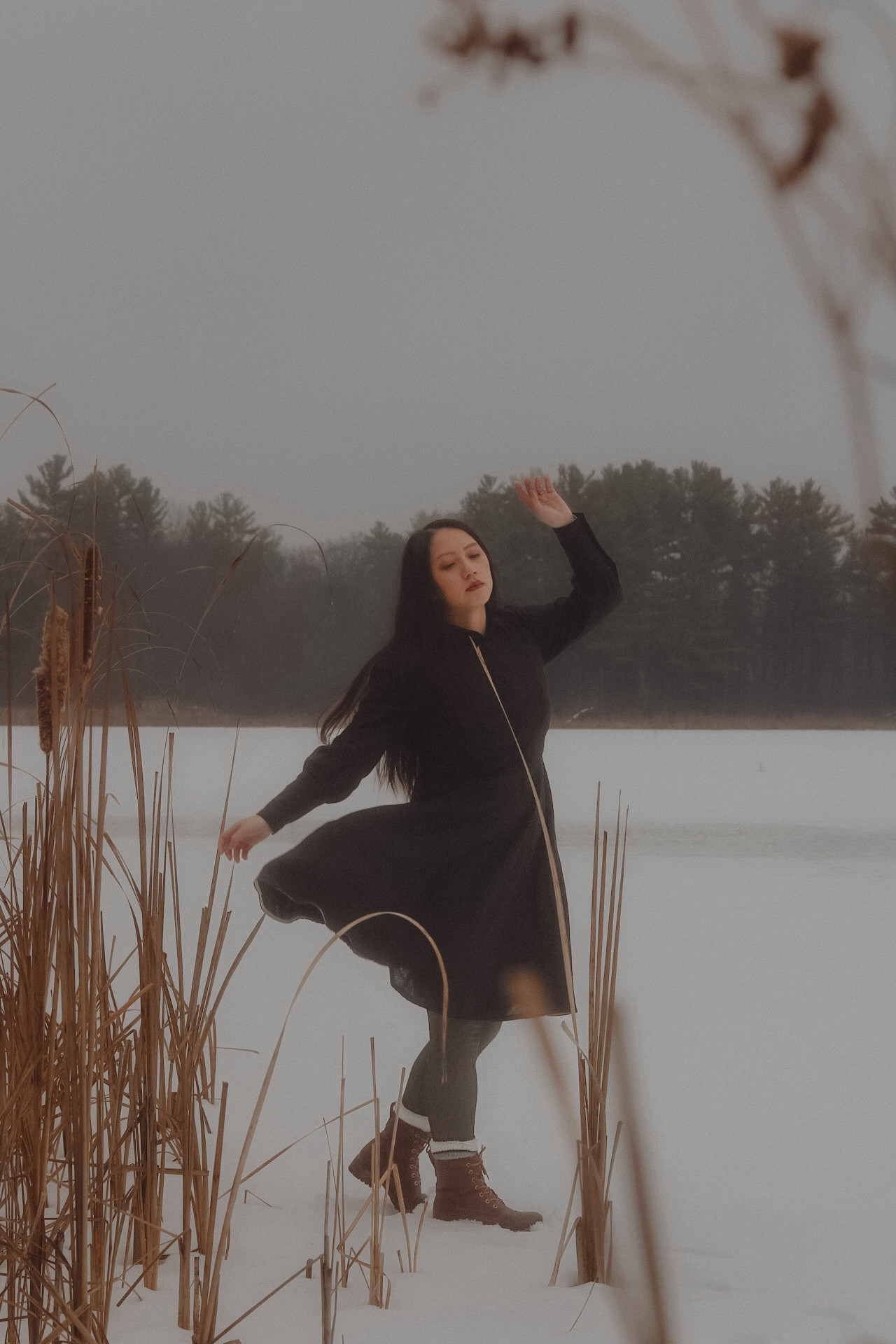 A girl in a black dress, twirling on a snowy frozen lake.