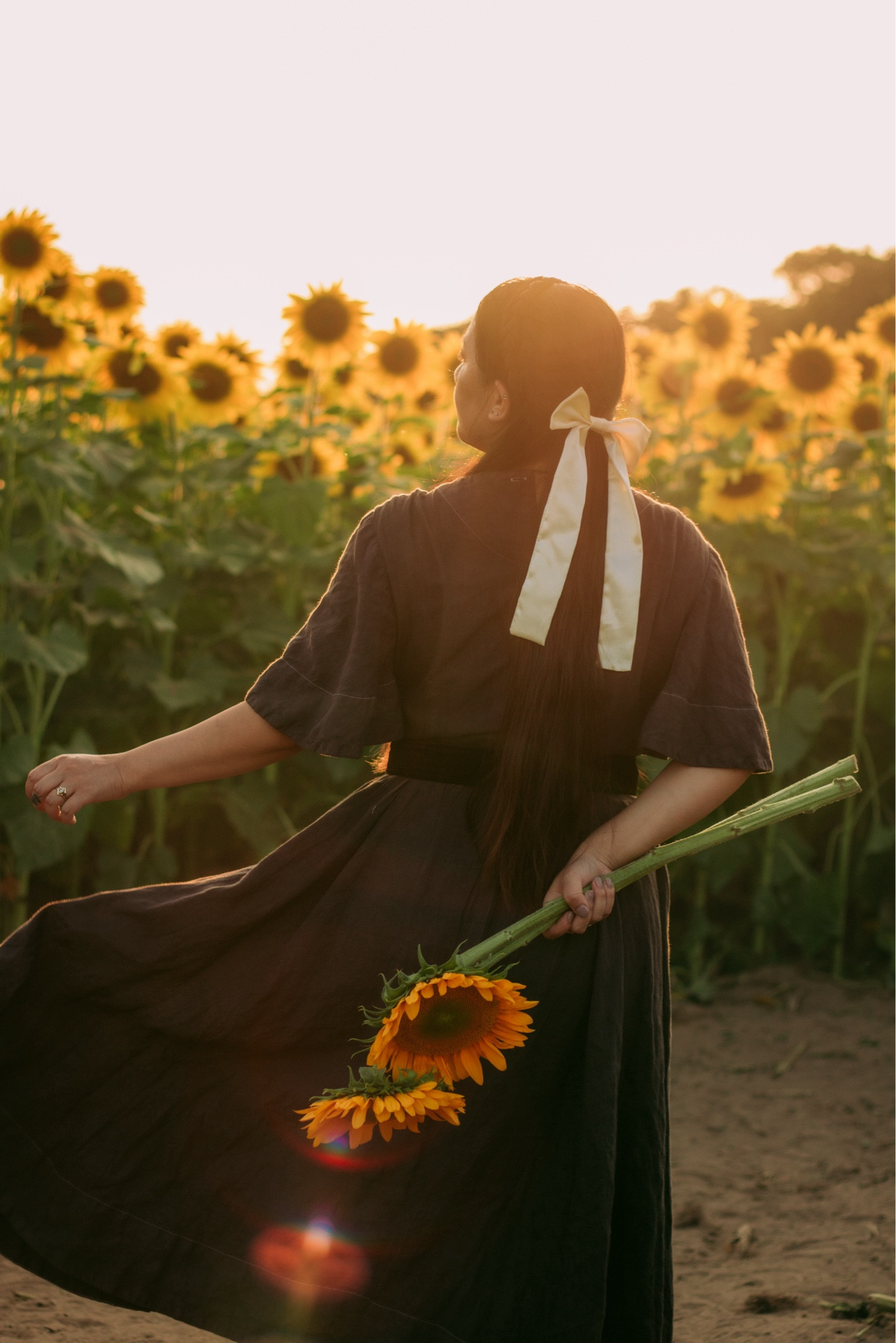 A girl twirling during golden hour at the sunflower farm.