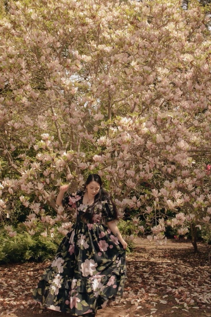 A girl in a black floral dress, dancing among the magnolias.