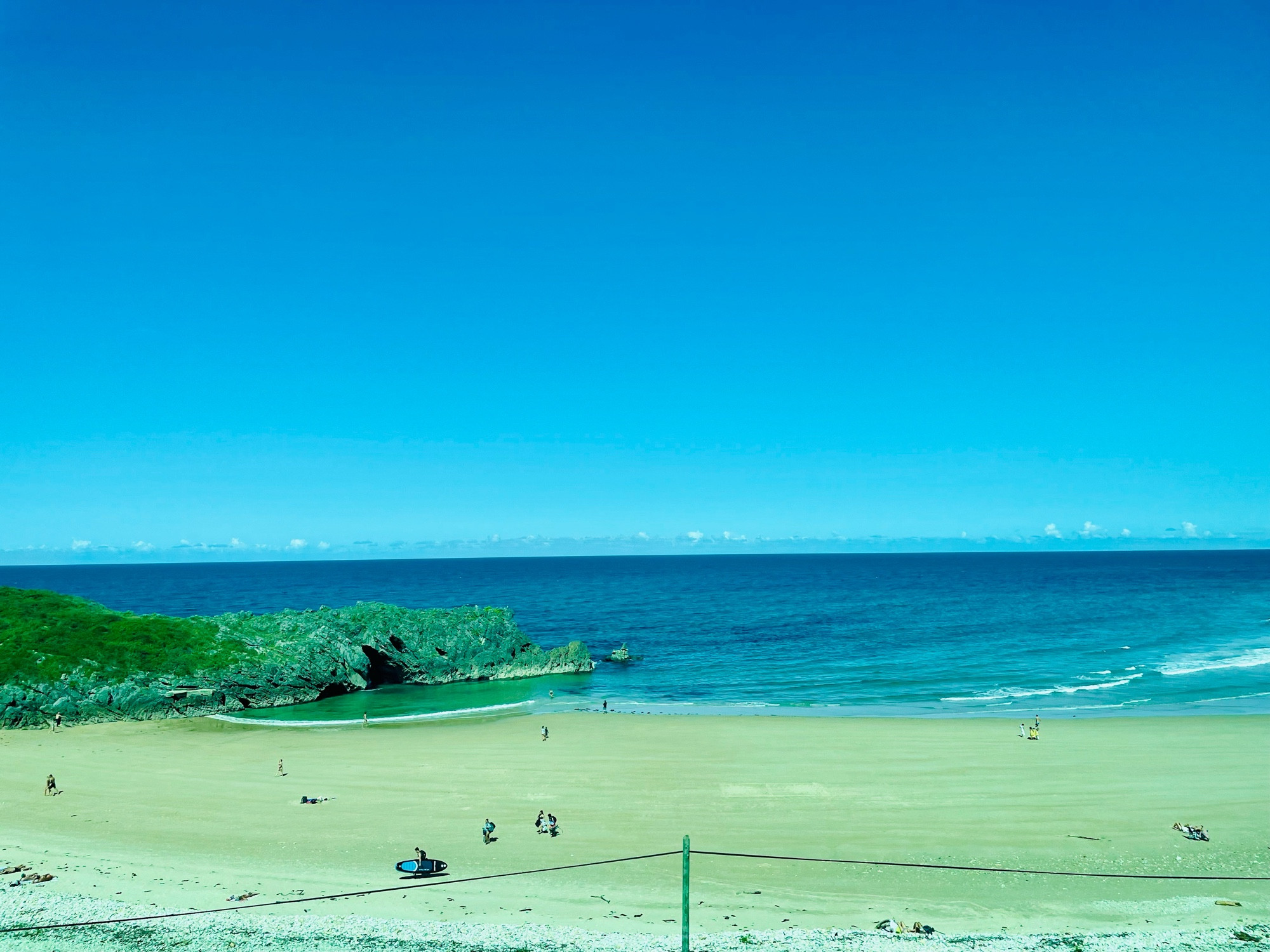 Sandy cove beach with golden sand and crystal clear blue waters.