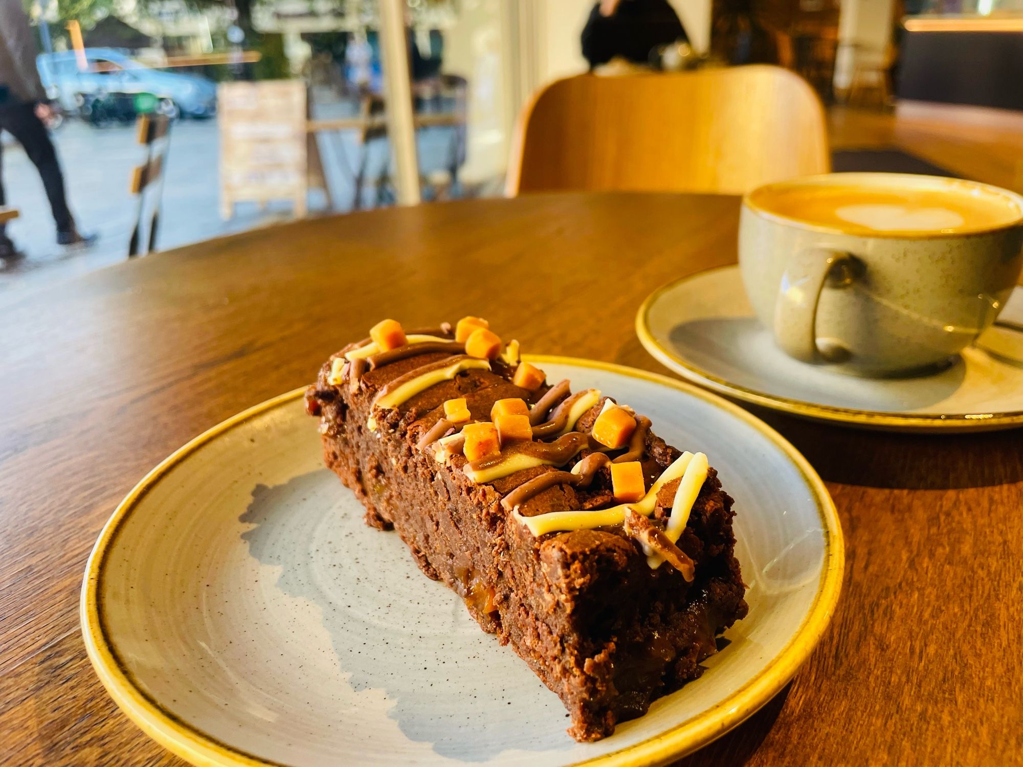 Slice of salted caramel chocolate brownie with a flat white cup of coffee.