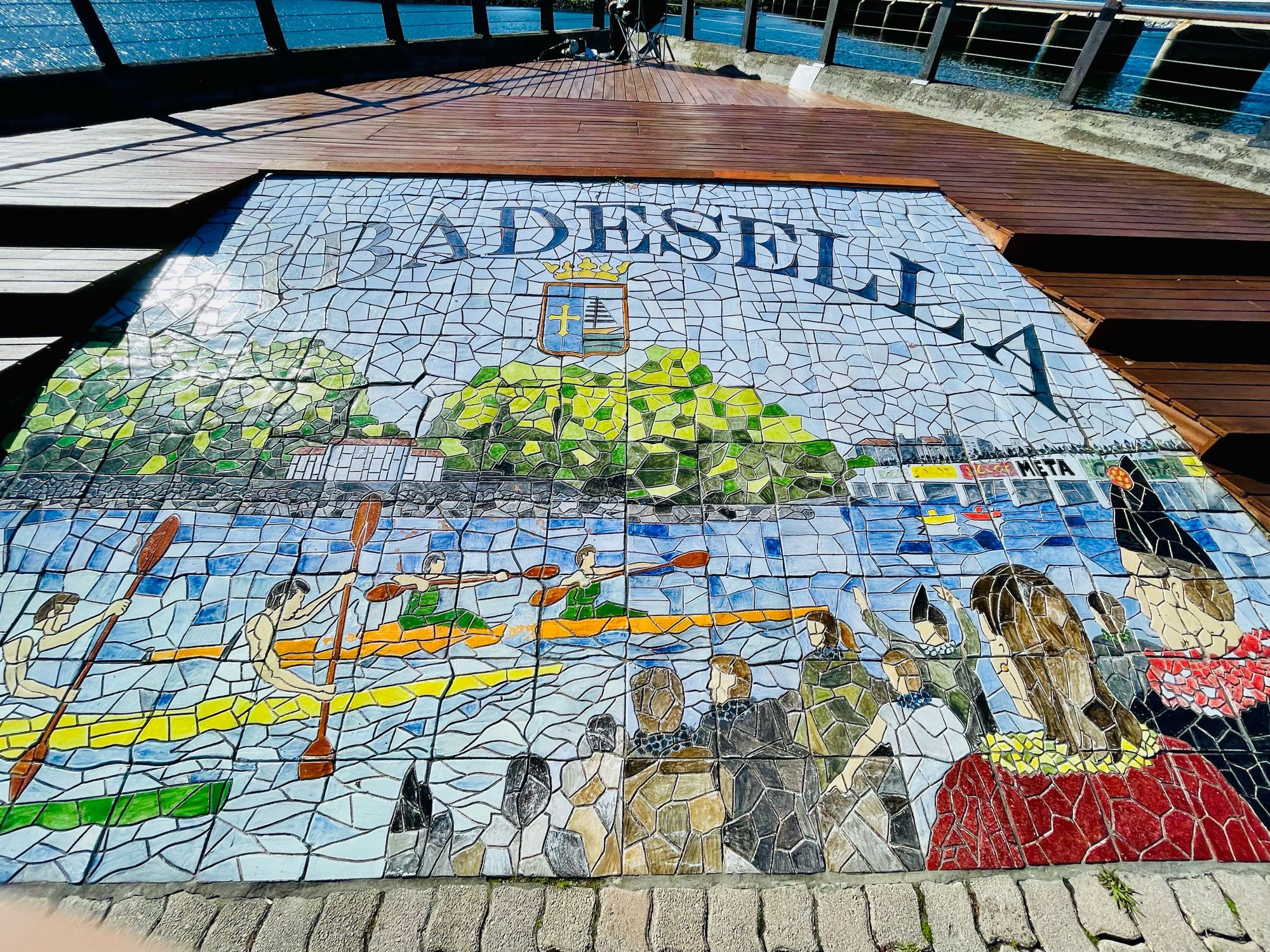 Mosaic of the village during the festival of canoeing. Canoeists are paddling down the sea with onlookers in the crowd.