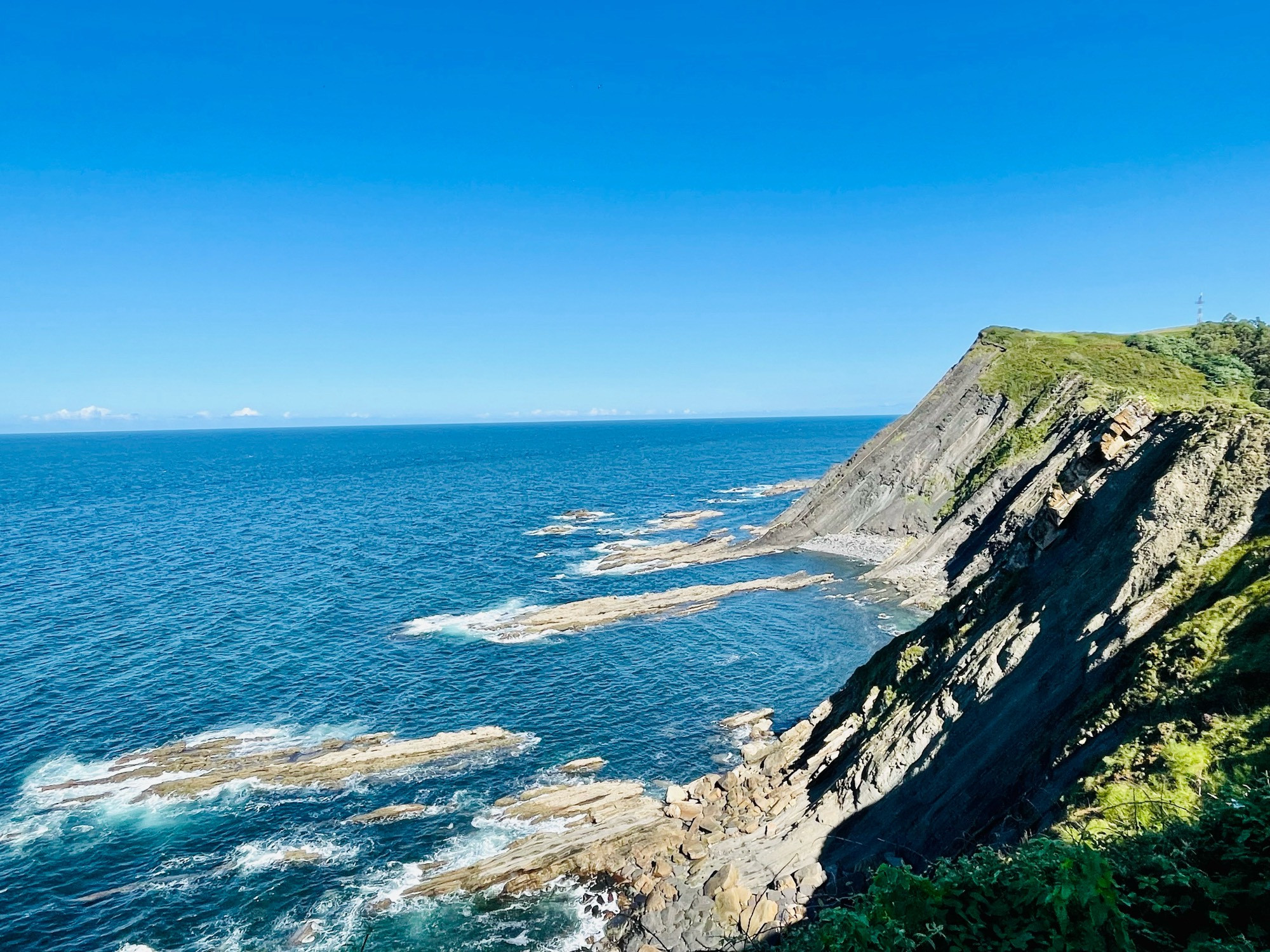 Rocky cliffs with the clear blue sea on a sunny day.