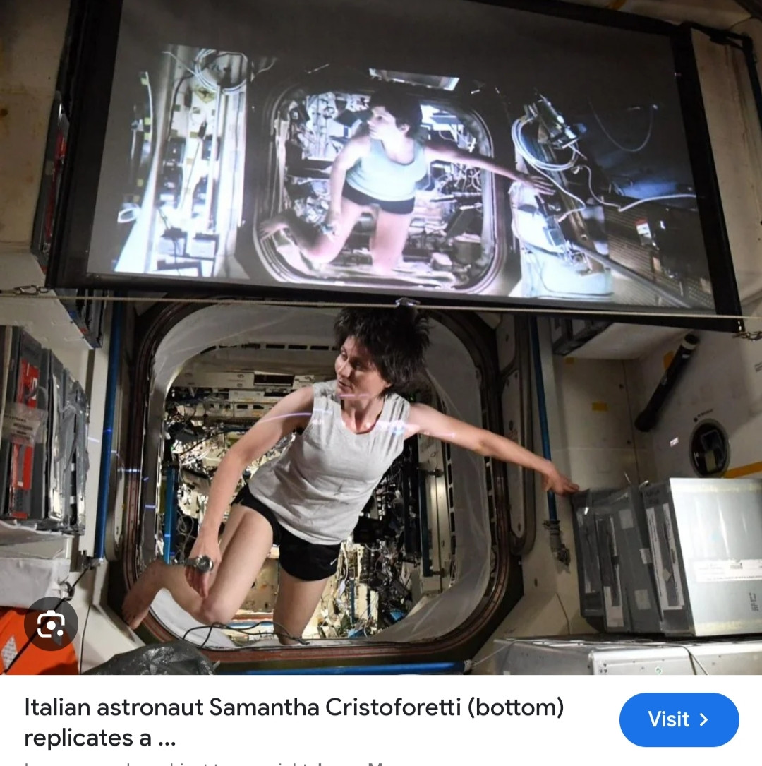 Italian astronaut Samantha Cristoforetti on the ISS cosplaying as Sandra Bullock in the movie Gravity, showing on a screen above her head.